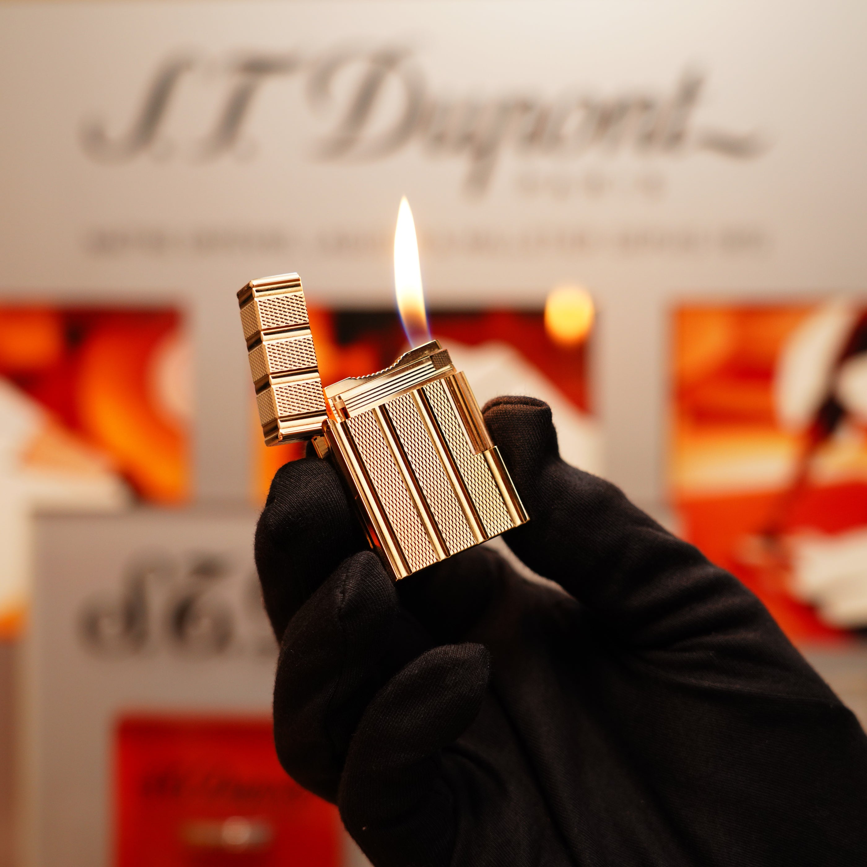 A gloved hand holding a lit S.T. Dupont Vintage 1990 lighter, featuring a 24k gold iconic Ligne 1 with small dots and line pattern.
