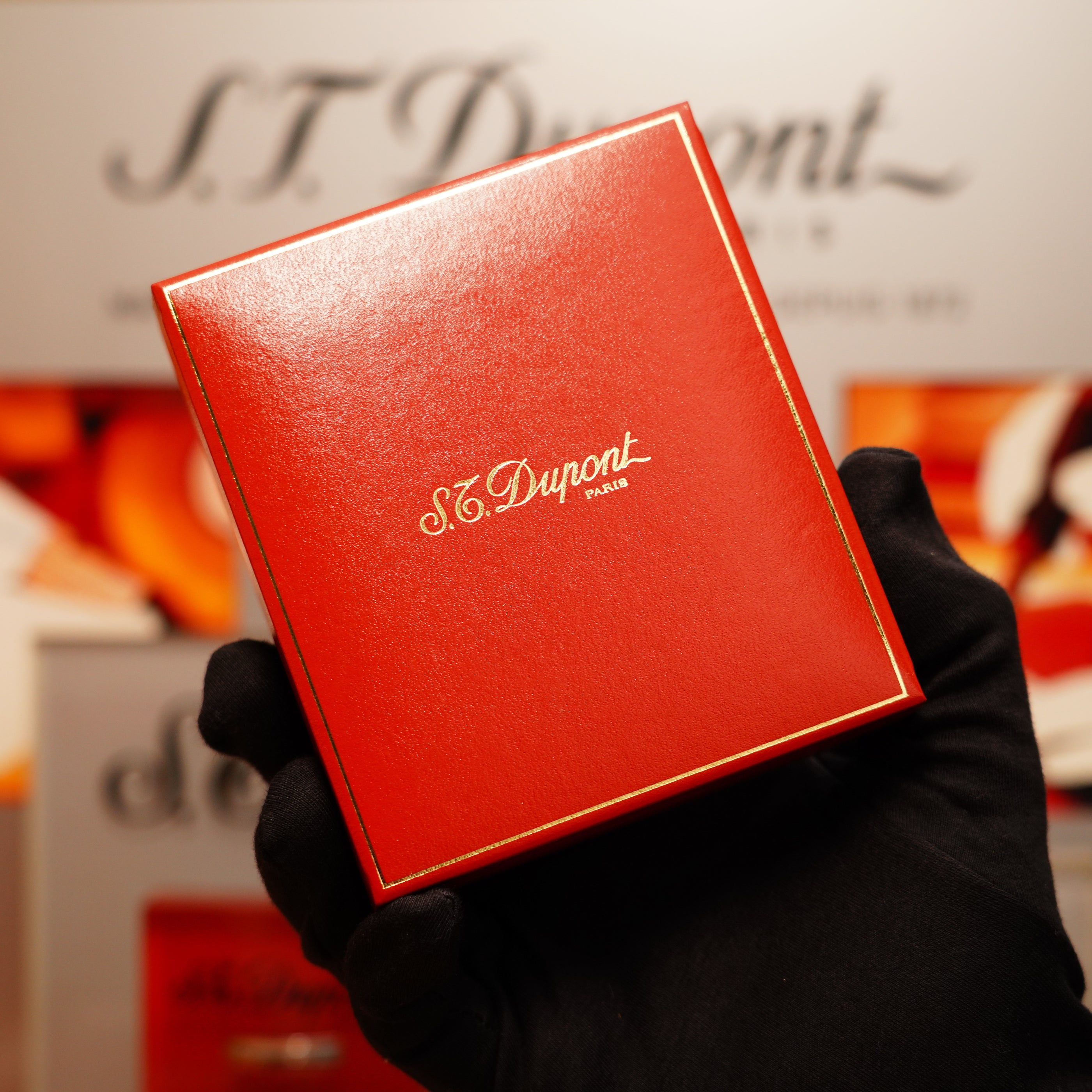 A gloved hand holds a red box featuring the S.T. Dupont Paris logo in gold lettering, housing the Vintage 1990 St Dupont 24k Gold Iconic Ligne 1 Small Dots and Line Pattern Lighter.