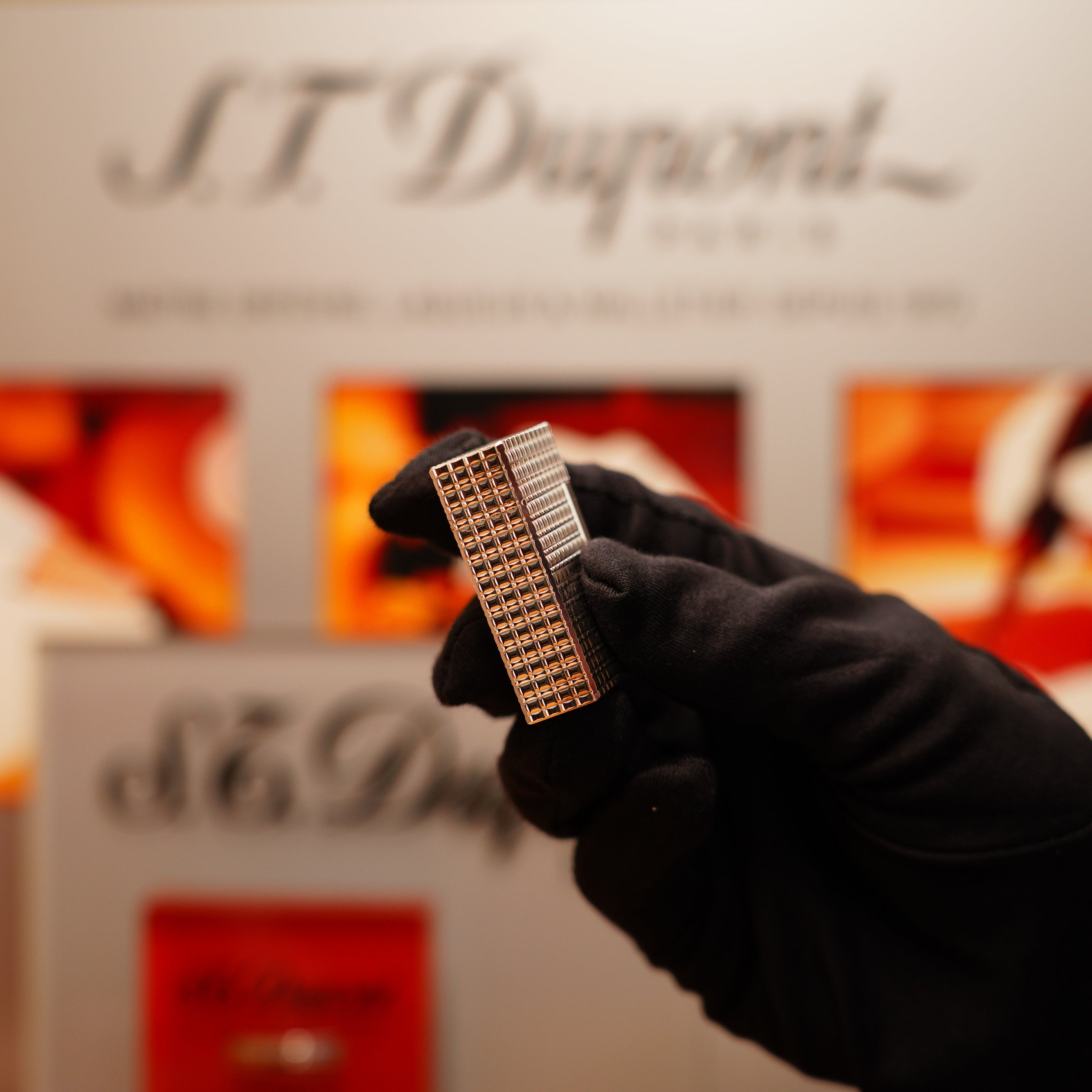 A gloved hand holds a Vintage 1990 S.T. Dupont Heavy Silver Finish Iconic Ligne 1 Rare Window Pattern Lighter against a blurred backdrop with the S.T. Dupont logo.