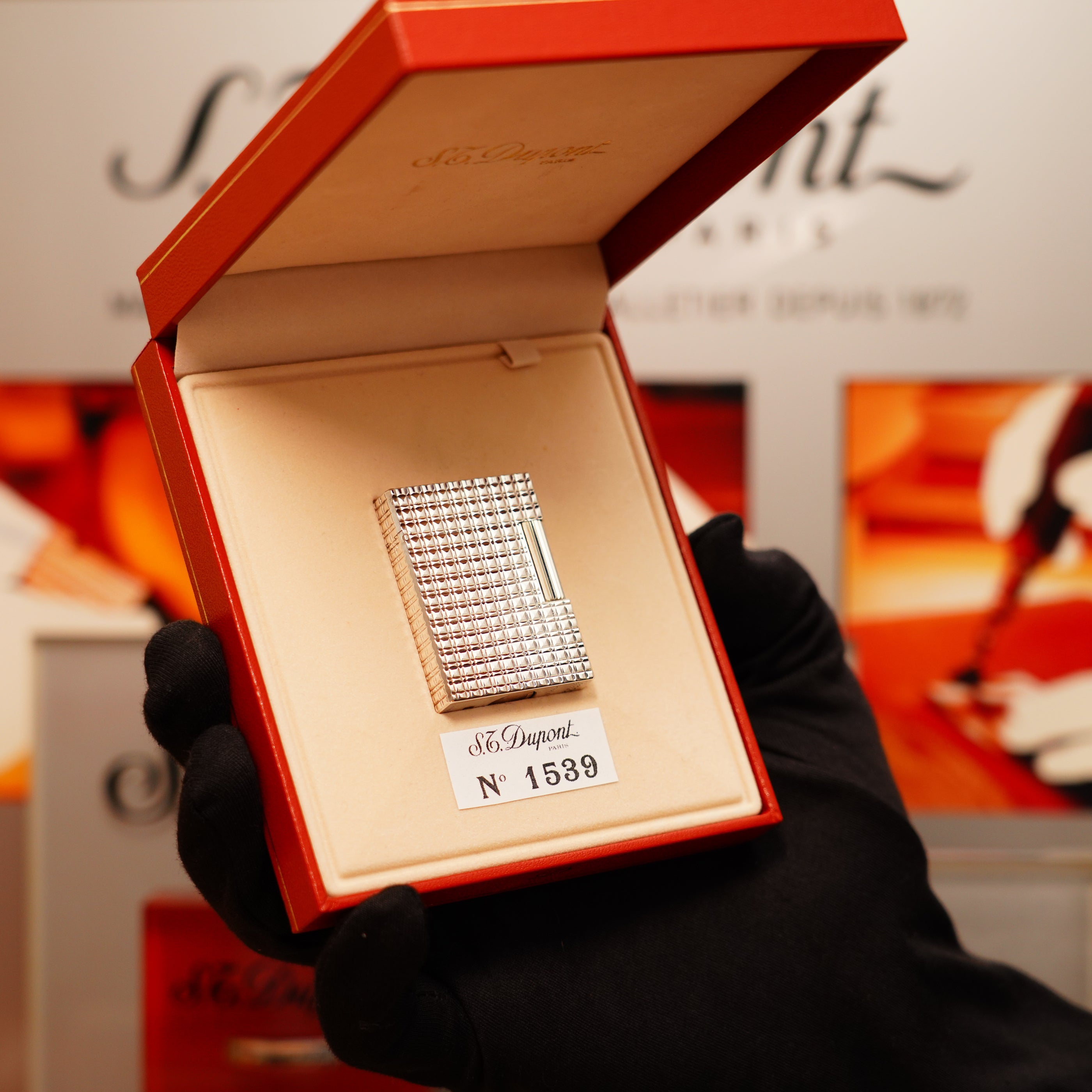 A gloved hand holds an open box containing a Vintage 1990 S.T. Dupont Iconic Ligne 1 lighter in heavy silver with a rare window pattern design.