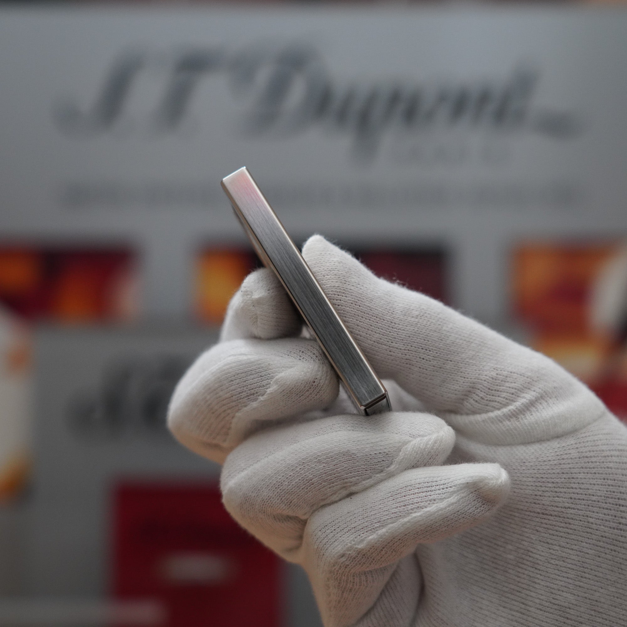 A hand holding a Vintage 2000 S.T. Dupont Palladium Décor High Tech 2000s Lighter in front of a store.