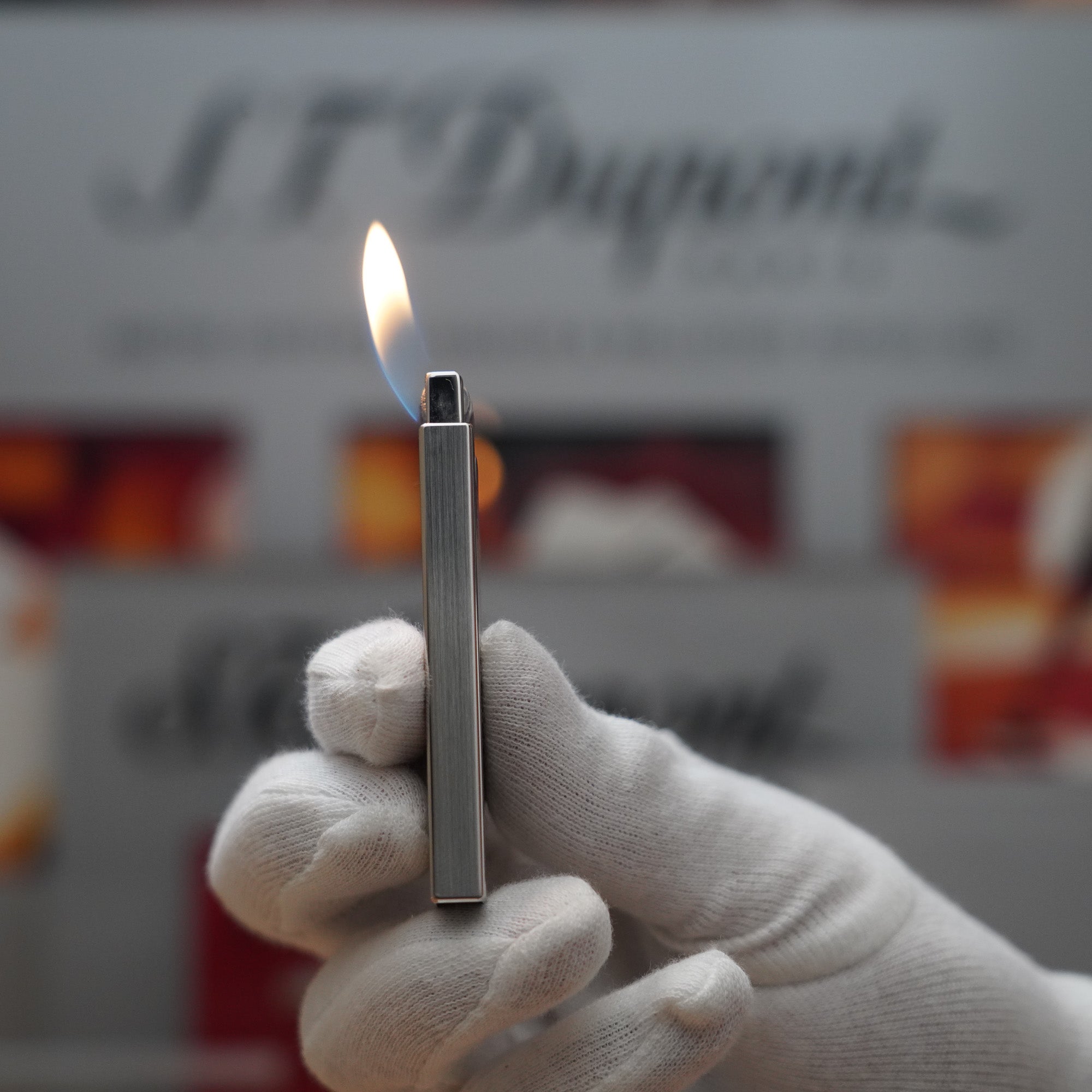 A Vintage 2000 S.T. Dupont Palladium Décor High Tech 2000s Lighter held in front of a box.