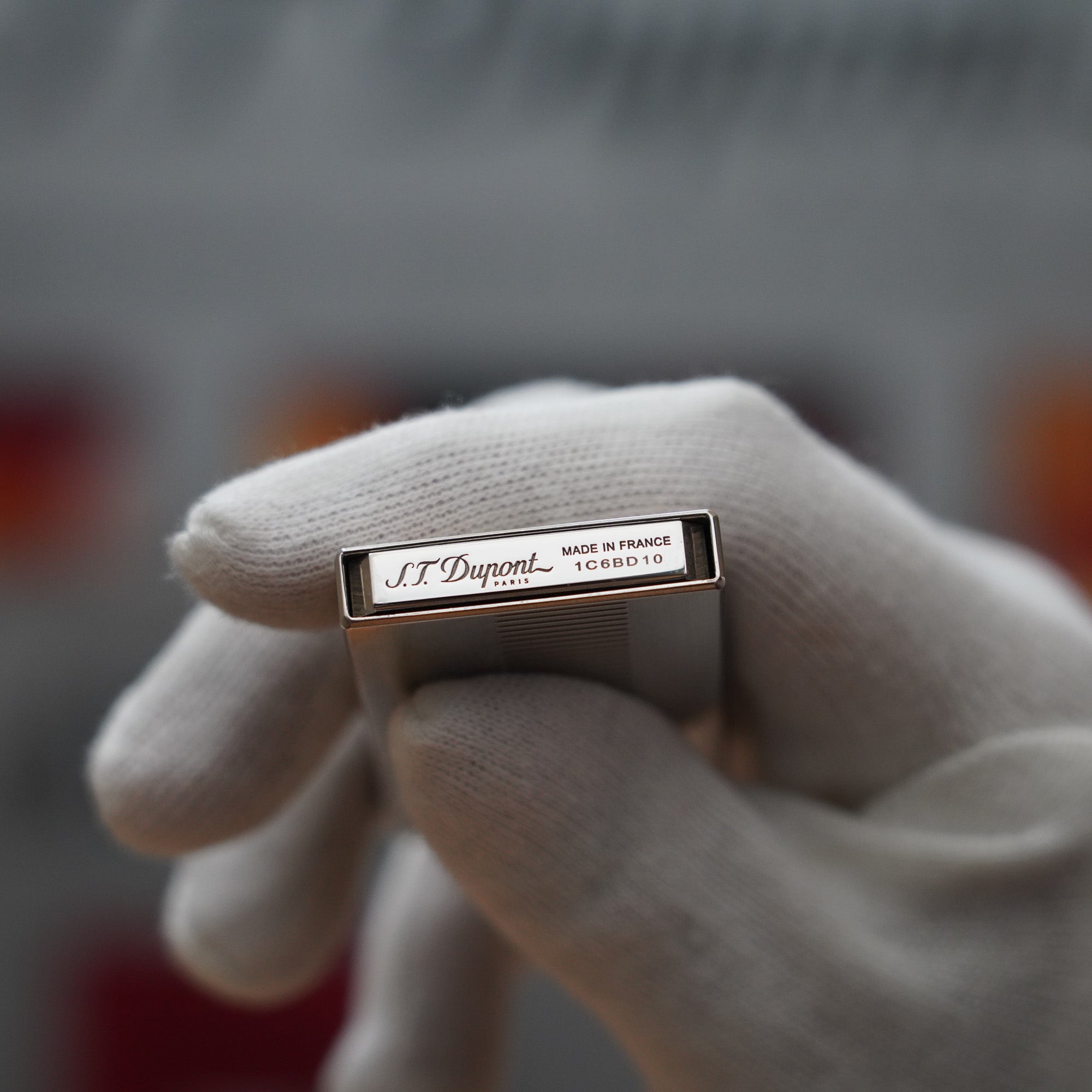 A person is holding a Vintage 2000 S.T. Dupont Palladium Décor High Tech 2000s Lighter with the brand name S.T. Dupont on it.
