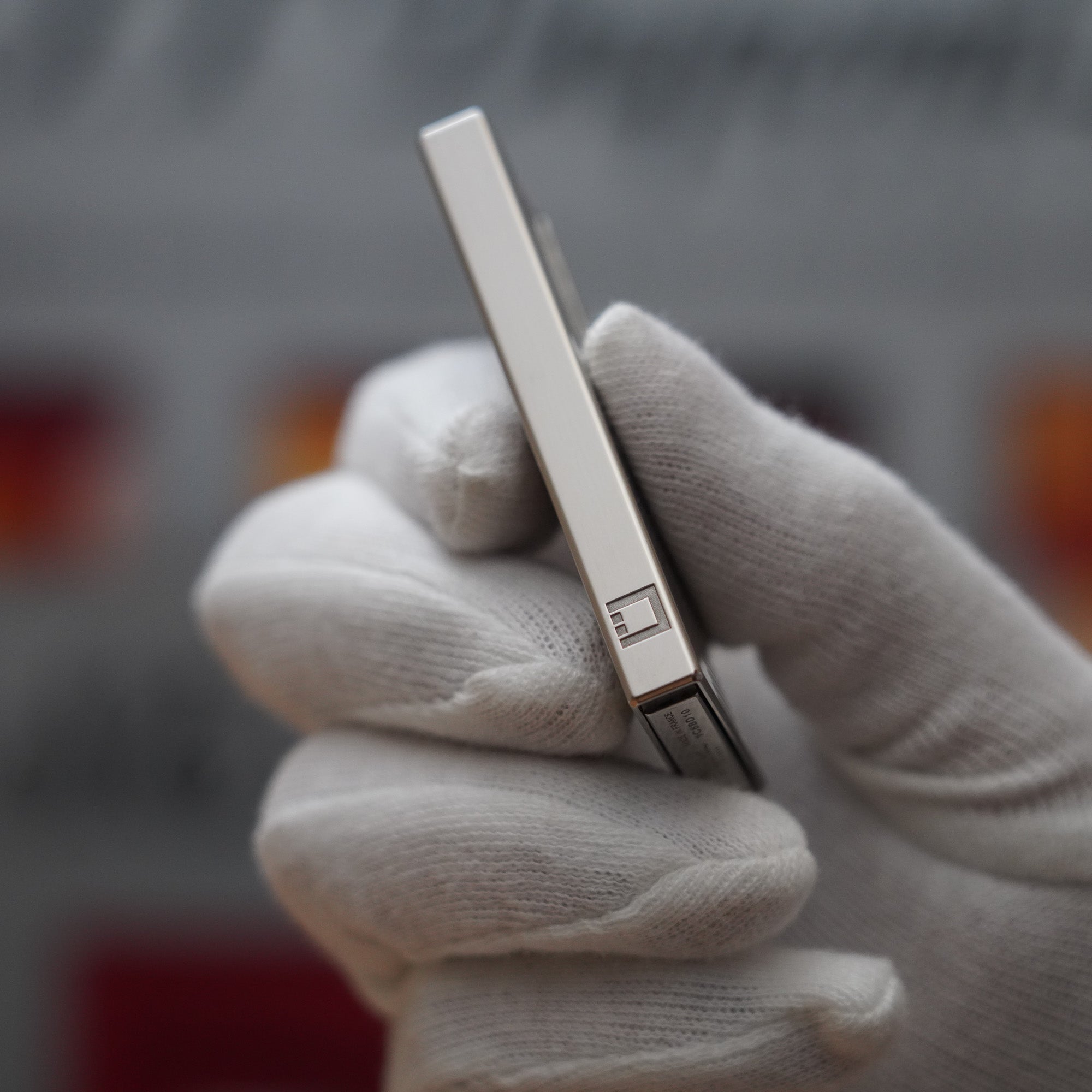 A person is holding up a Vintage 2000 S.T. Dupont Palladium Décor High Tech 2000s Lighter in white gloves.