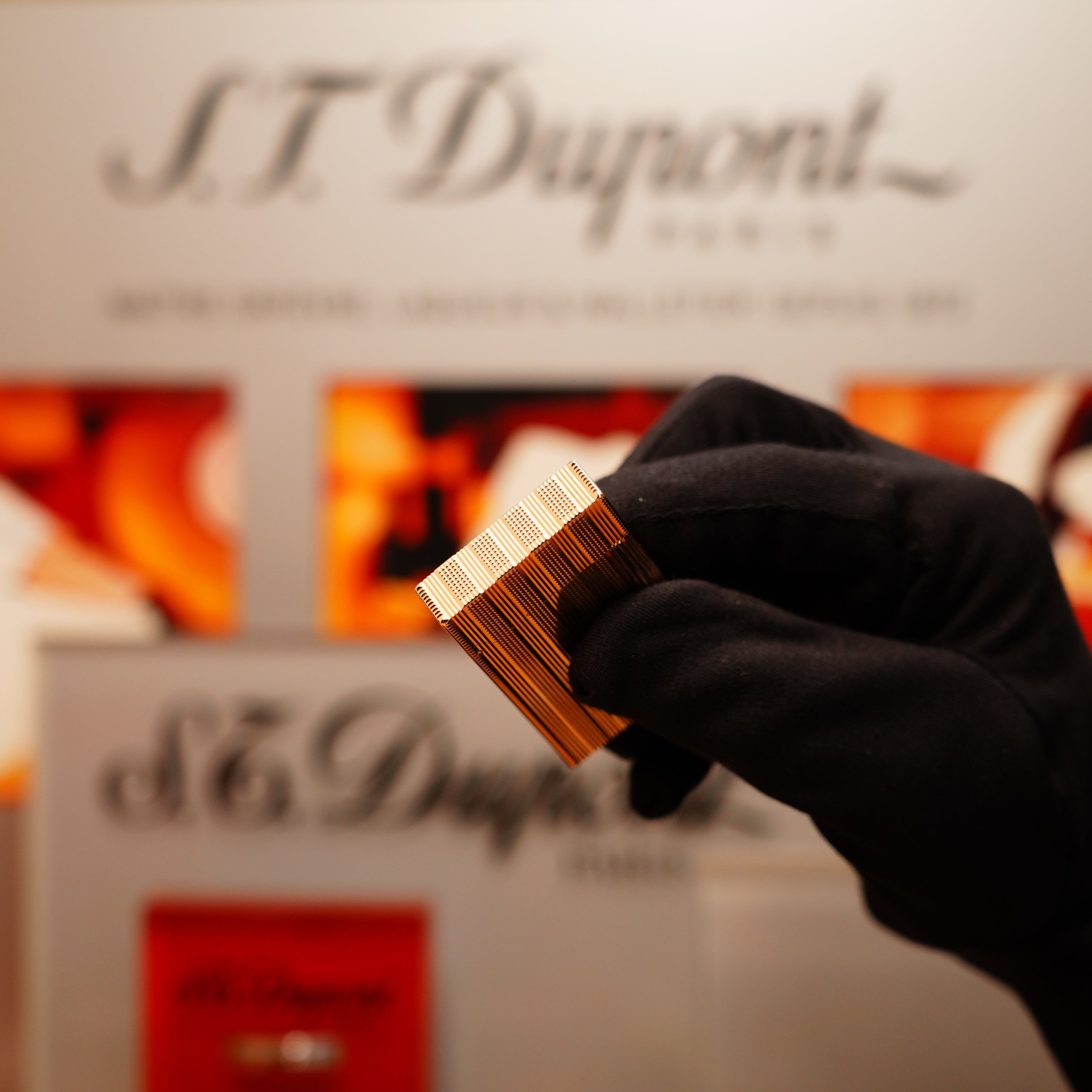 A gloved hand holds a Vintage 1978 S.T. Dupont 24k Gold Lignes Verticales Pointes Diamants Large Ligne 2 Lighter in front of a blurred display.