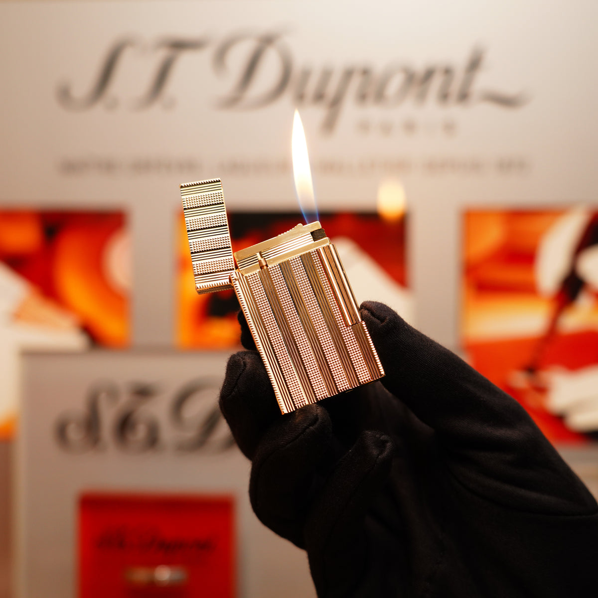A gloved hand holds a lit lighter, revealing the branding "S.T. Dupont" in the background. The product is a Vintage 1978 St Dupont 24k Gold Lignes Verticales Pointes Diamants Large Ligne 2 Lighter by S.T. Dupont.