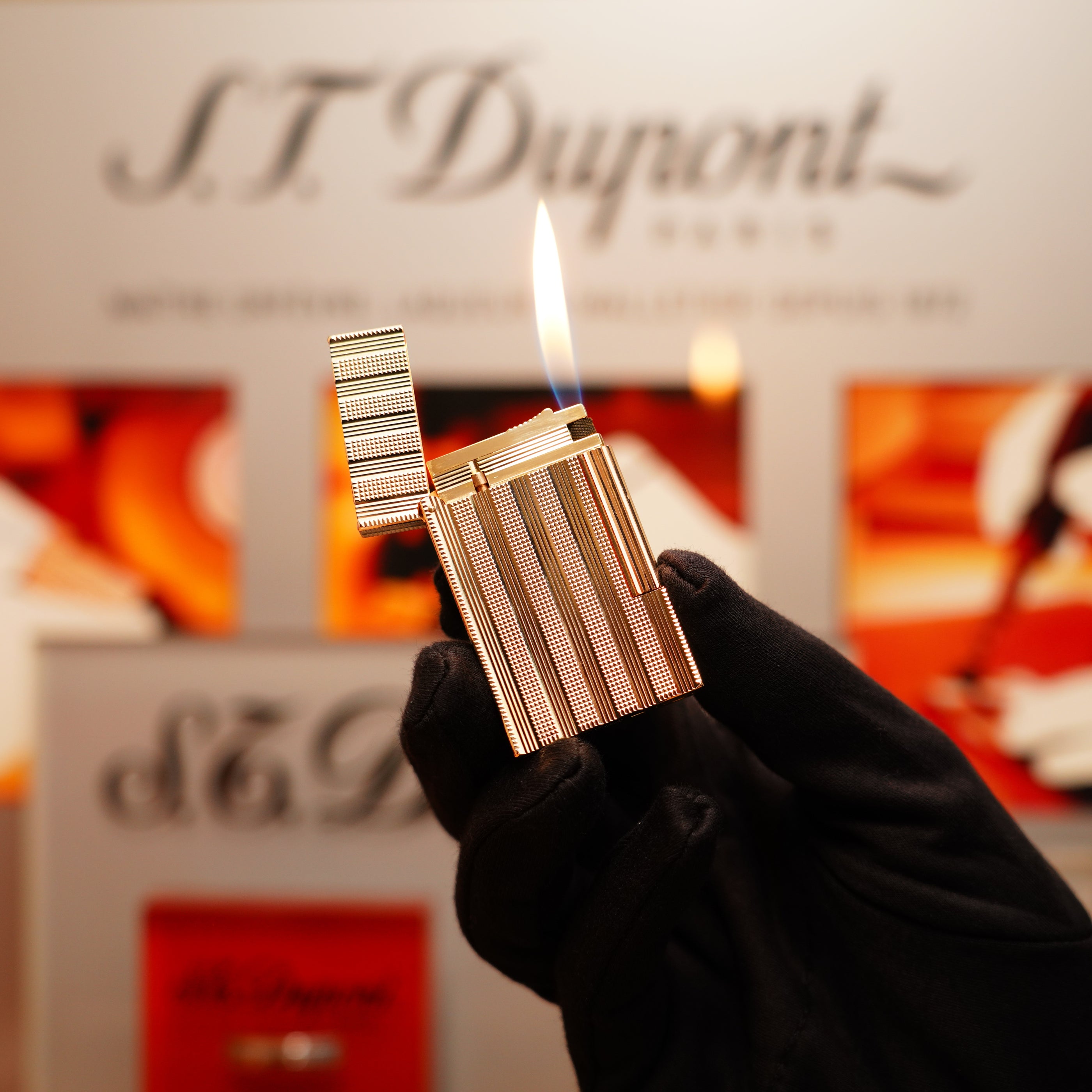 A gloved hand holds a lit lighter, revealing the branding "S.T. Dupont" in the background. The product is a Vintage 1978 St Dupont 24k Gold Lignes Verticales Pointes Diamants Large Ligne 2 Lighter by S.T. Dupont.