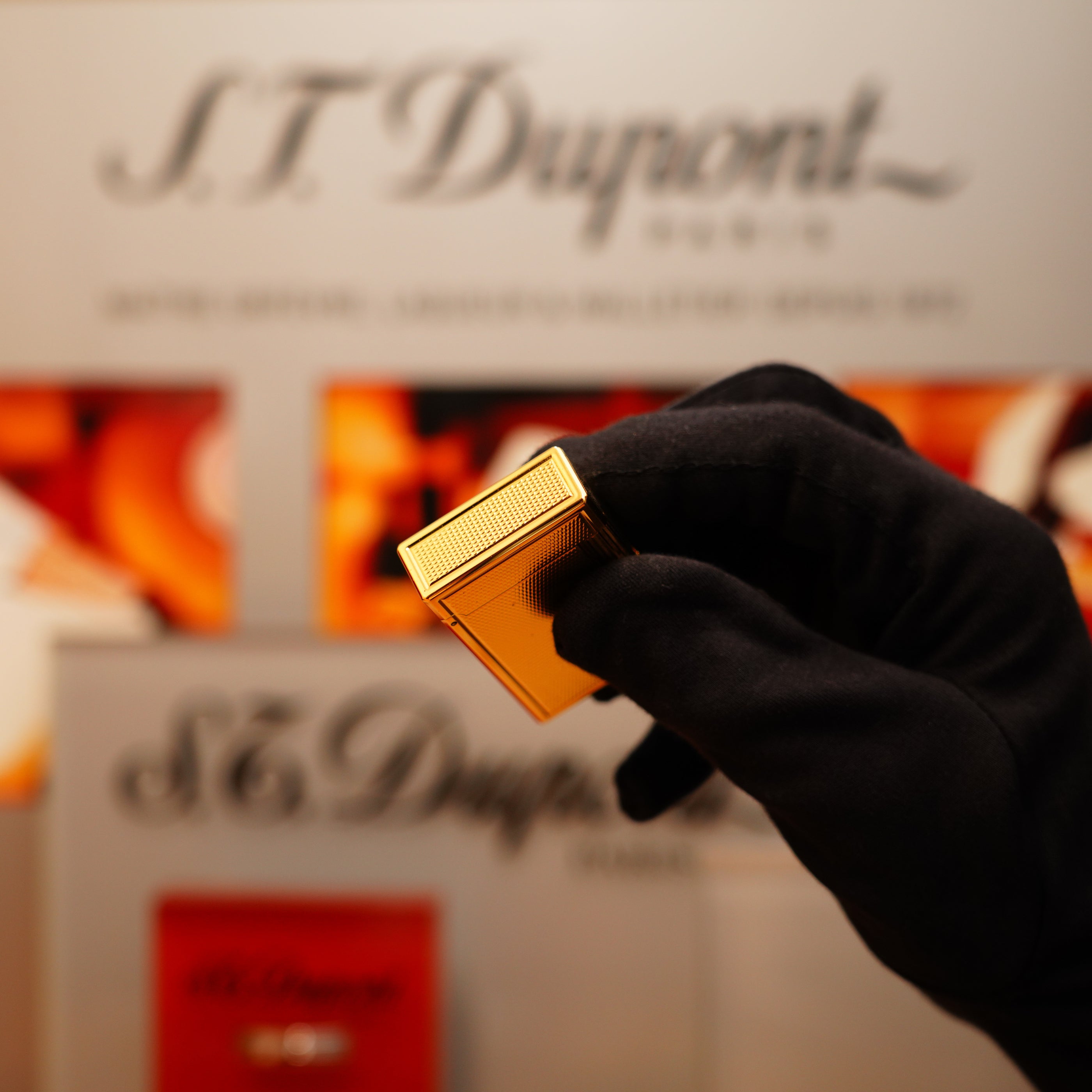 A gloved hand holds a Vintage 1990 S.T. Dupont 24k Large Grain d'Org Iconic Ligne 1 Heavy Finish Lighter.