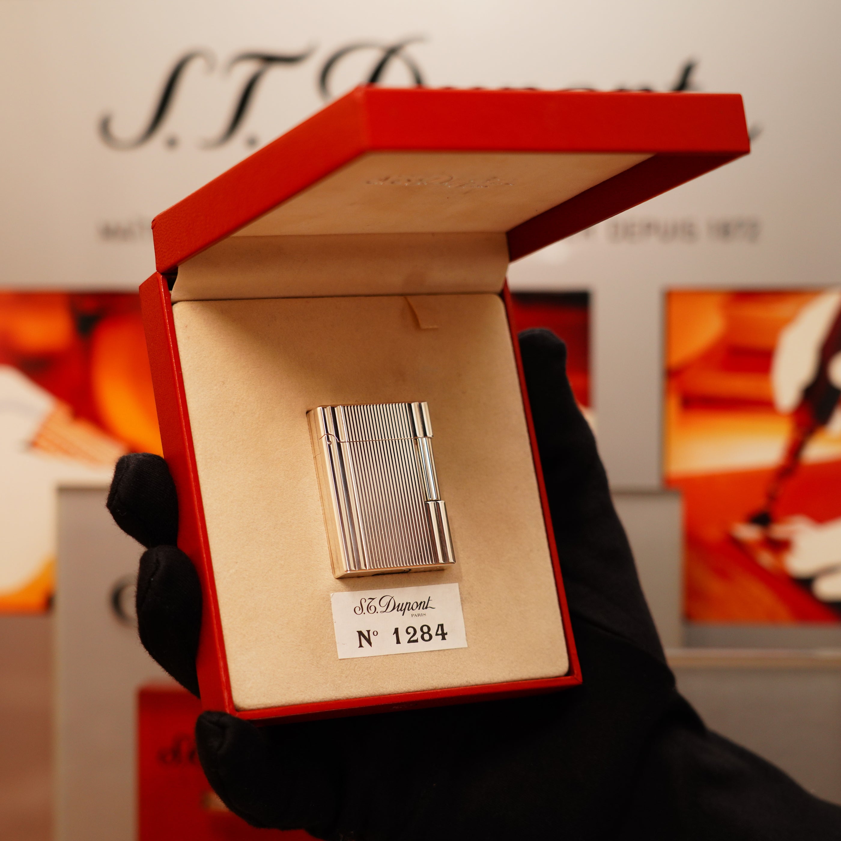 A gloved hand holds an open red box displaying a metal S.T. Dupont lighter labeled as a Vintage 2000 St Dupont Heavy Silver Finish Small iconic Ligne 1 Vertical Ligne Lighter.