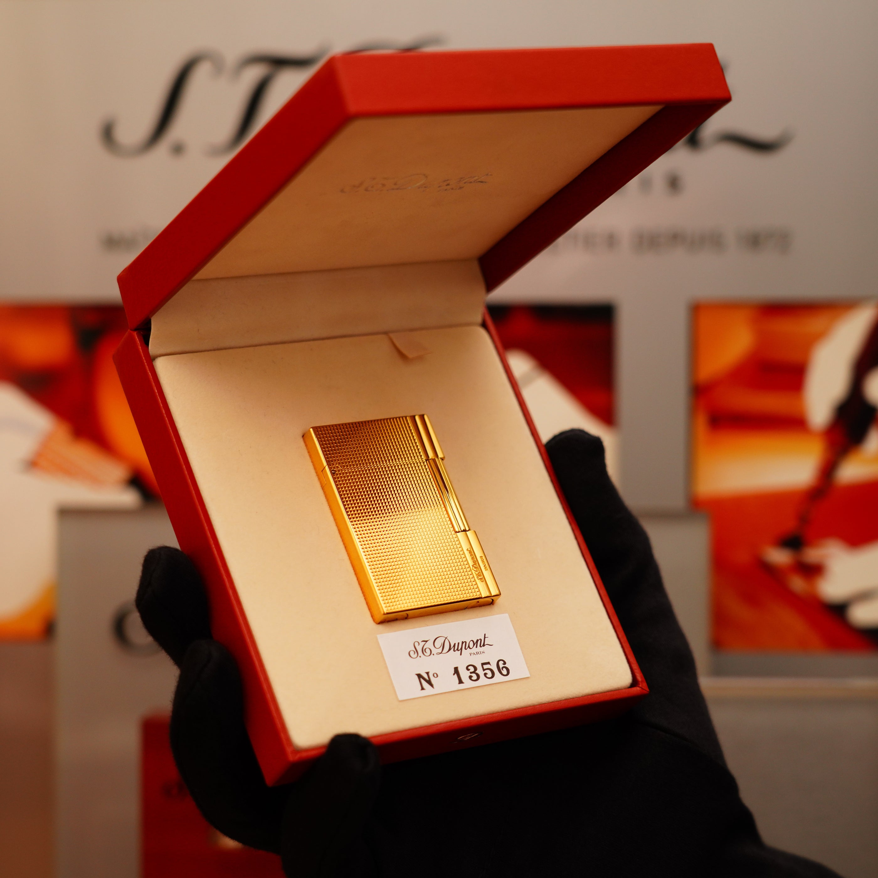 A gloved hand holds an open red box containing a Vintage 2002 S.T. Dupont Gatsby Ligne 2 Lighter with a rare heavy 24k gold finish and vertical line pattern, numbered 1856.