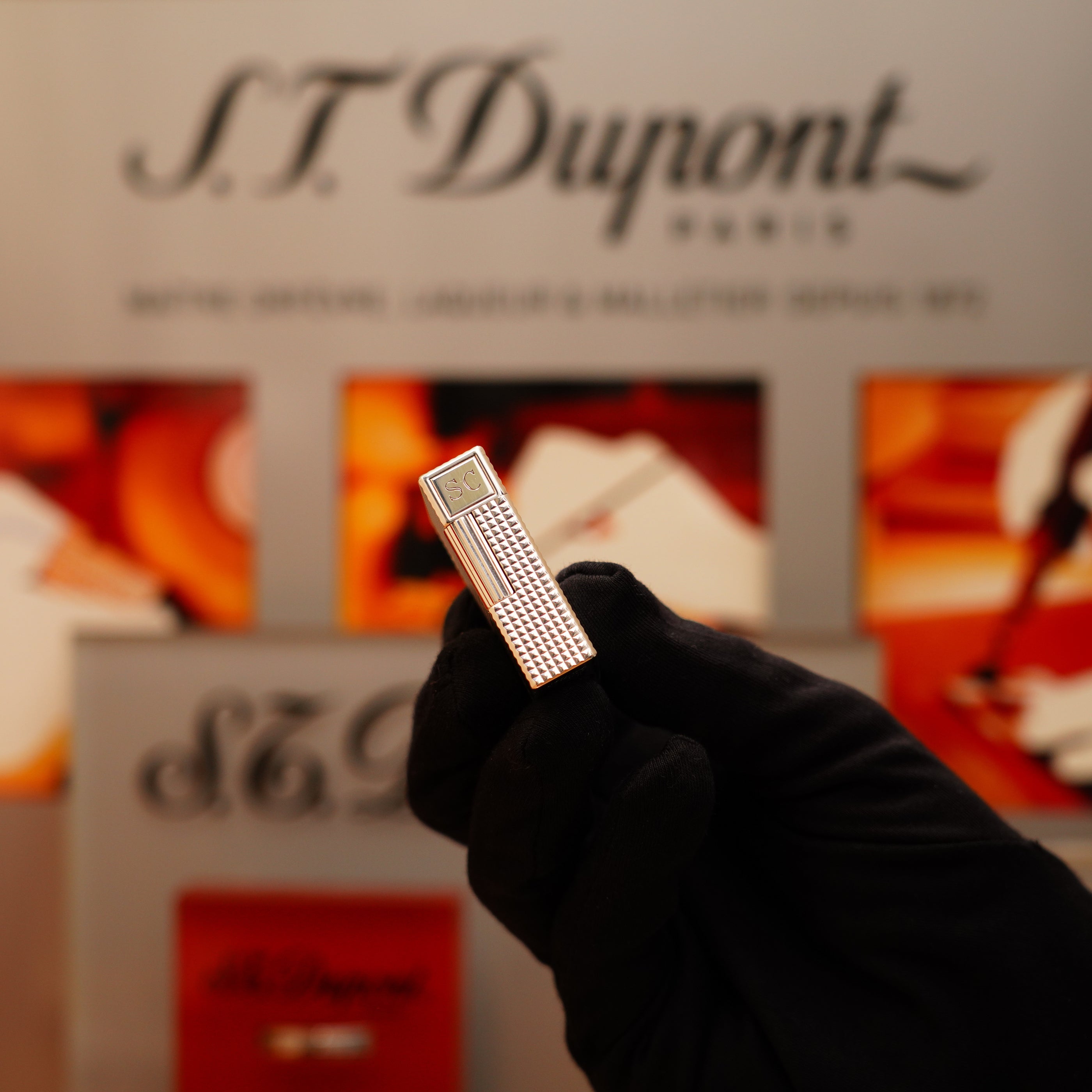 A gloved hand holds a Vintage 1996 S.T. Dupont Ligne 1 lighter, featuring a Diamond Head pattern and heavy silver finish, set against a blurred background with the S.T. Dupont logo.