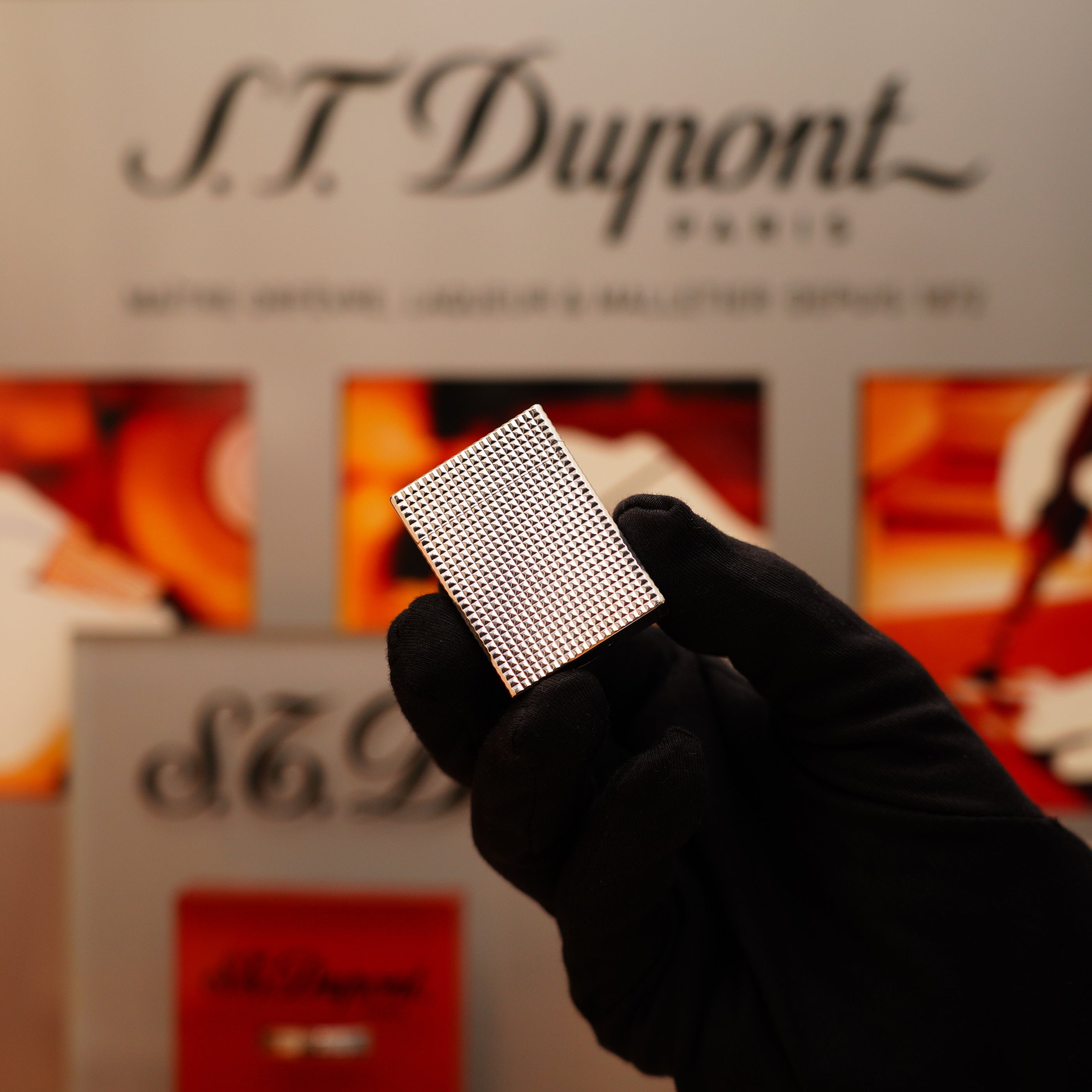 A gloved hand holds a Vintage 1996 S.T. Dupont Ligne 1 lighter with a Diamond Head pattern and heavy silver finish in front of a blurred background, featuring "S.T. Dupont Paris.