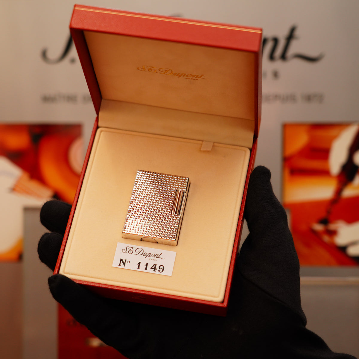 A gloved hand holds a Vintage 1996 S.T. Dupont Ligne 1 Diamond Head Pattern small silver lighter in an open red box marked with serial number 1149.