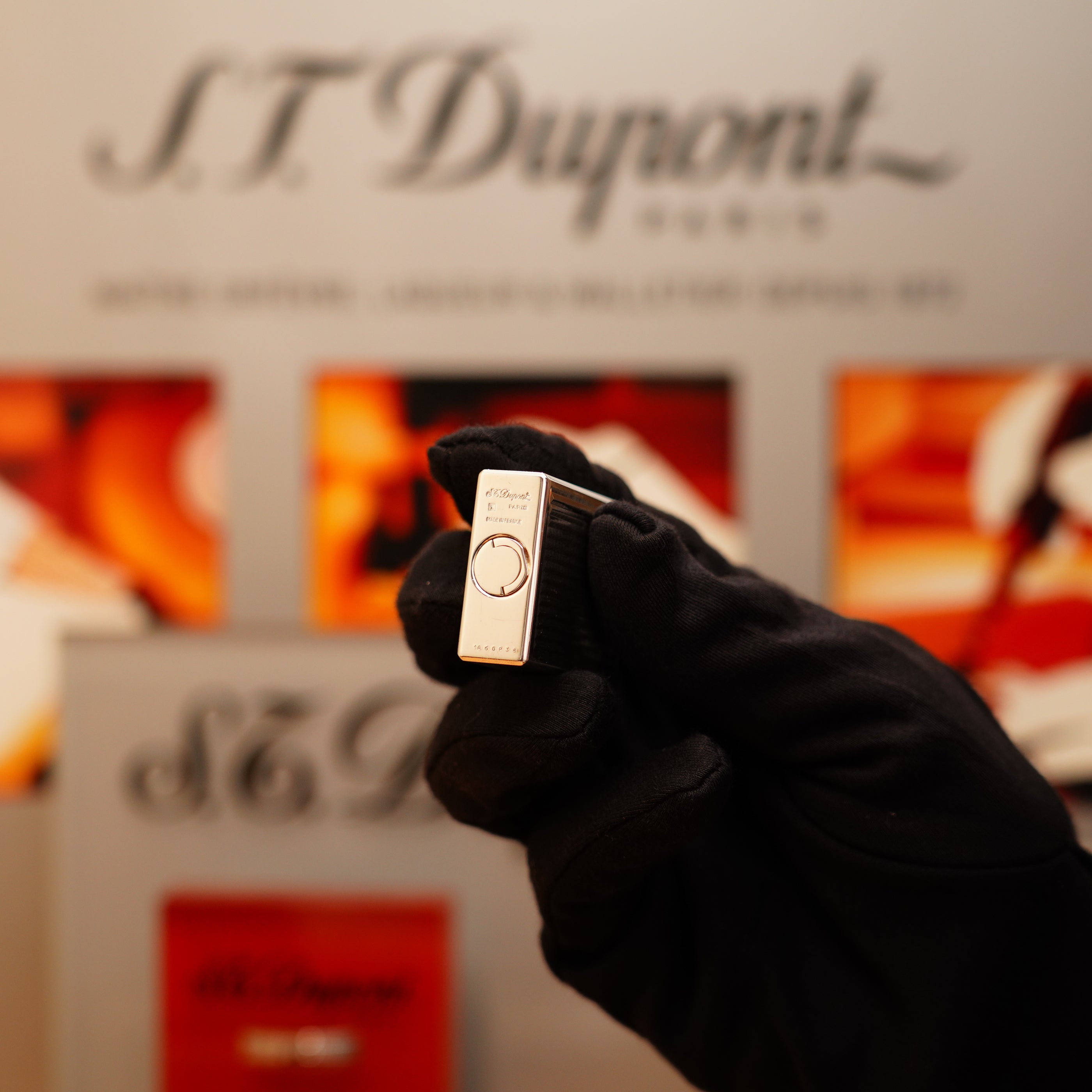 A gloved hand holds a Vintage 1996 S.T. Dupont Ligne 1 lighter with a rare heavy silver finish and vertical line pattern in front of a blurred S.T. Dupont display.