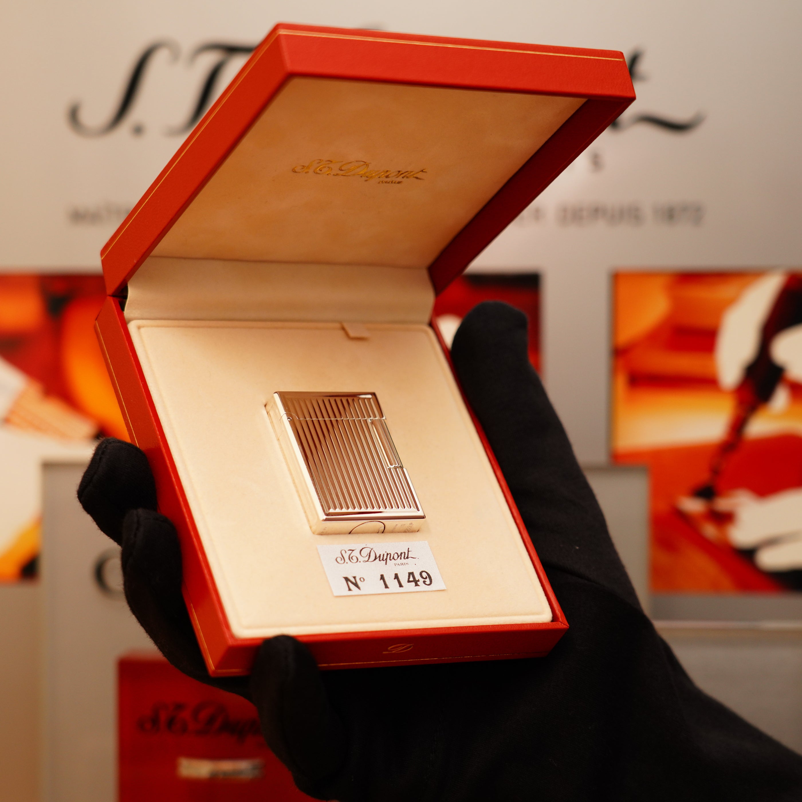A hand in a black glove holds an open red box containing a Vintage 1996 S.T. Dupont Ligne 1 lighter with a rare heavy silver finish and vertical line pattern, numbered 1489.