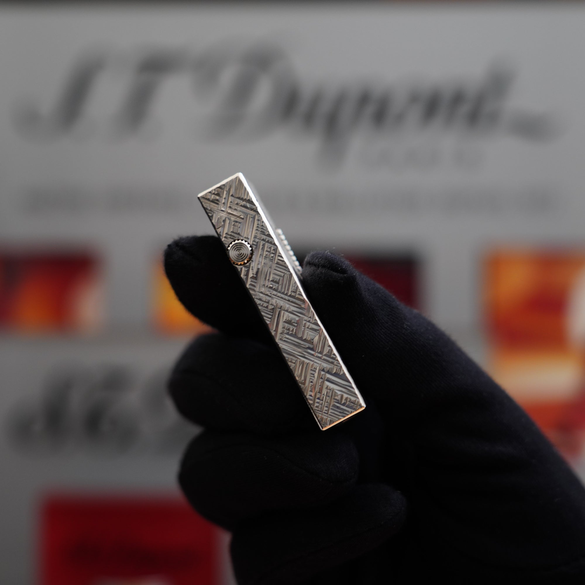 A person holding a Vintage 1980 Dunhill Rollagas Silver Plated Florentine Pattern Lighter in front of a box, a collector's item.