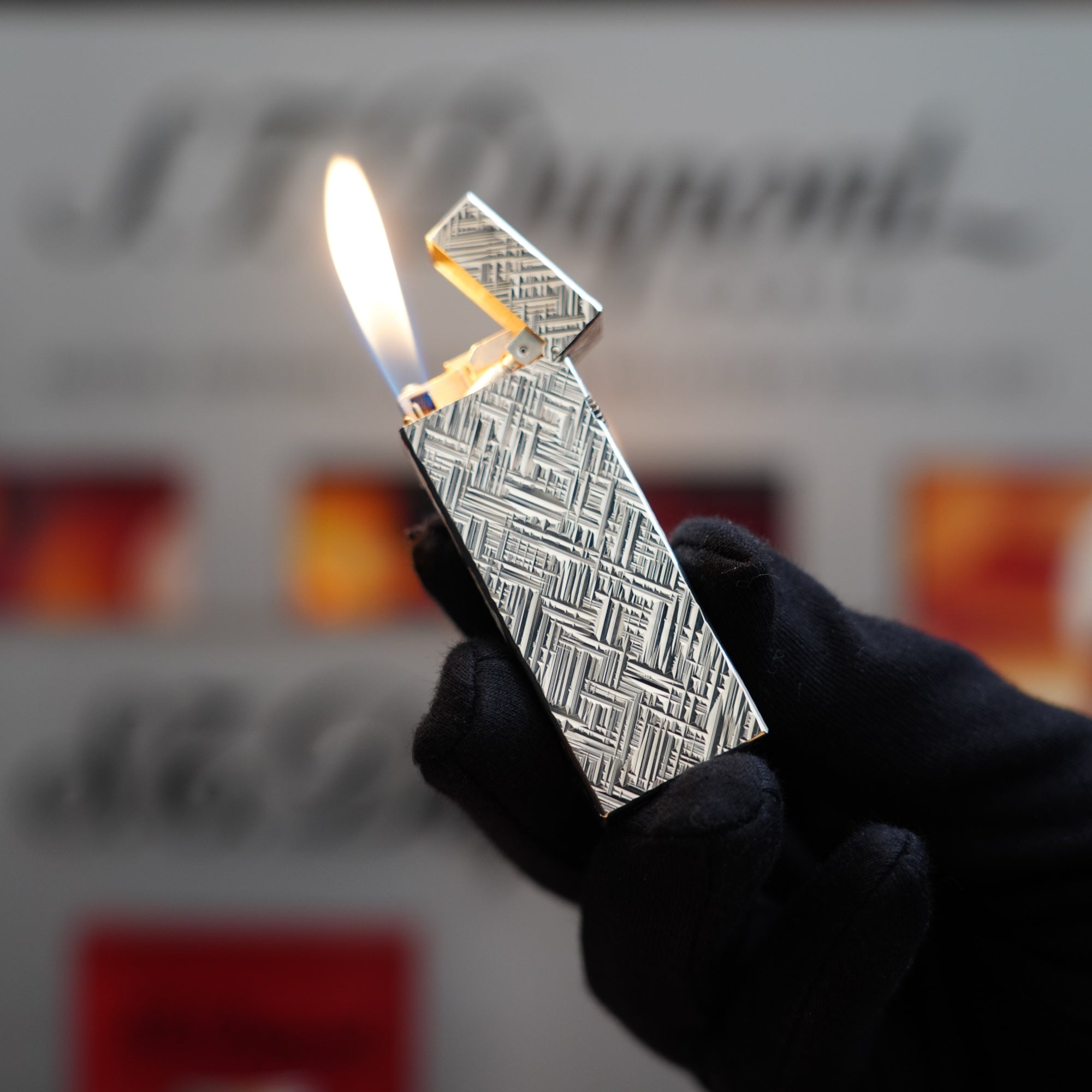 A person is holding a Vintage 1980 Dunhill Rollagas Silver Plated Florentine Pattern Lighter in front of a box.