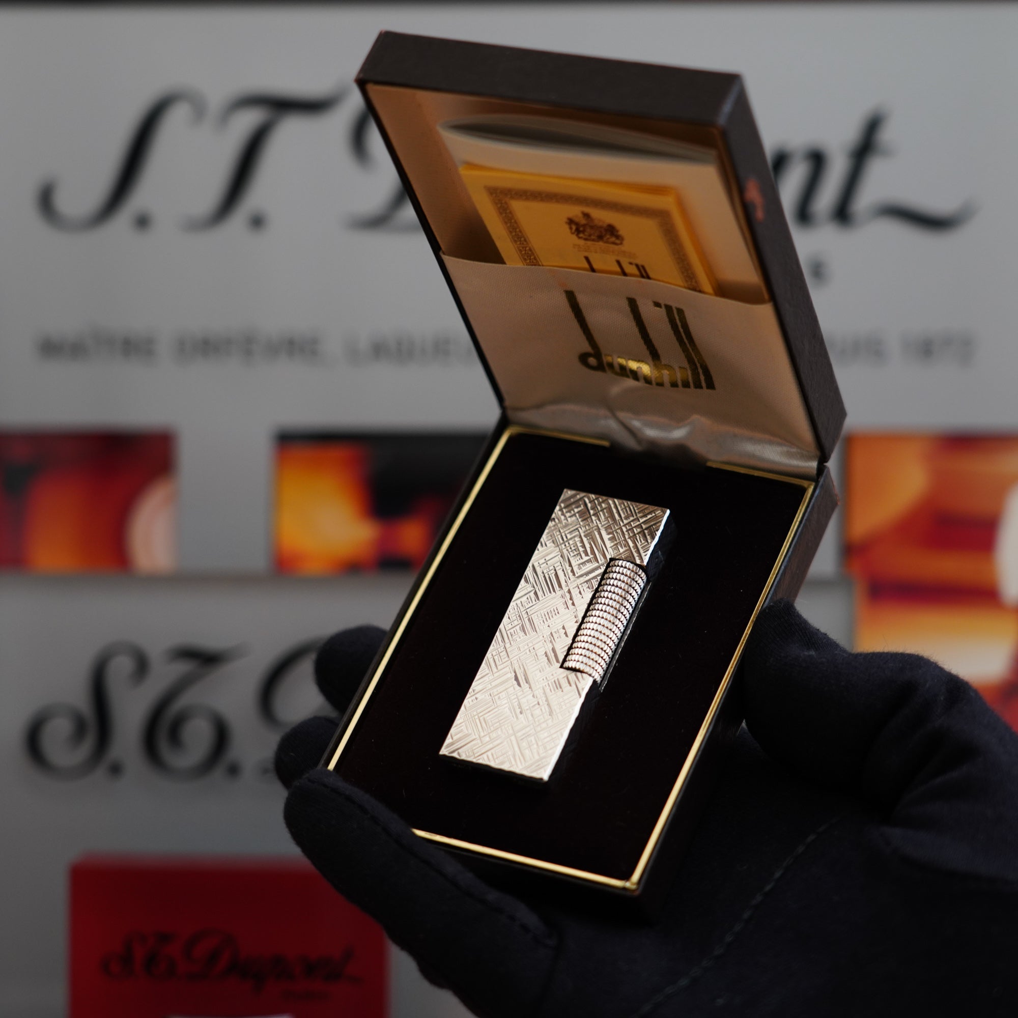A person is holding a vintage 1980 Dunhill Rollagas Silver Plated Florentine Pattern lighter in a box.