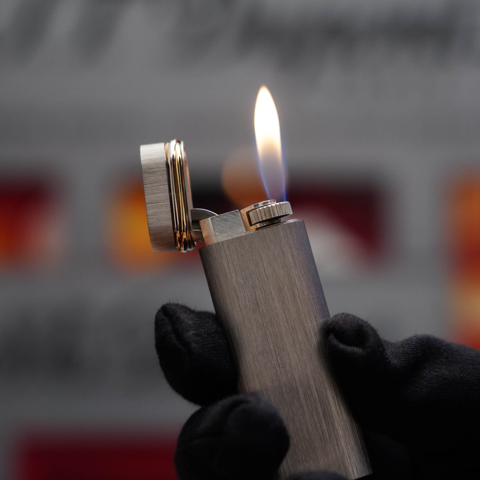 A person holding a Cartier Vintage 1980 Palladium Plated 18k Trinity ring Lighter with a flame in it.