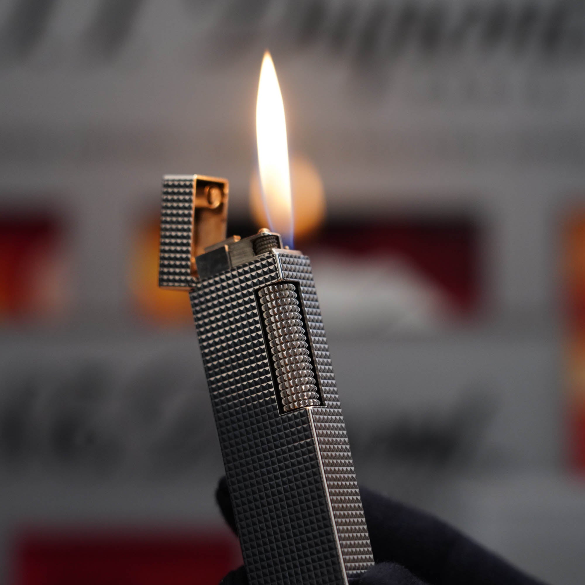 A person is holding up a Vintage 1970 Dunhill table lighter Diamond Head Silver Plated Long Boy Lighter with a flame.