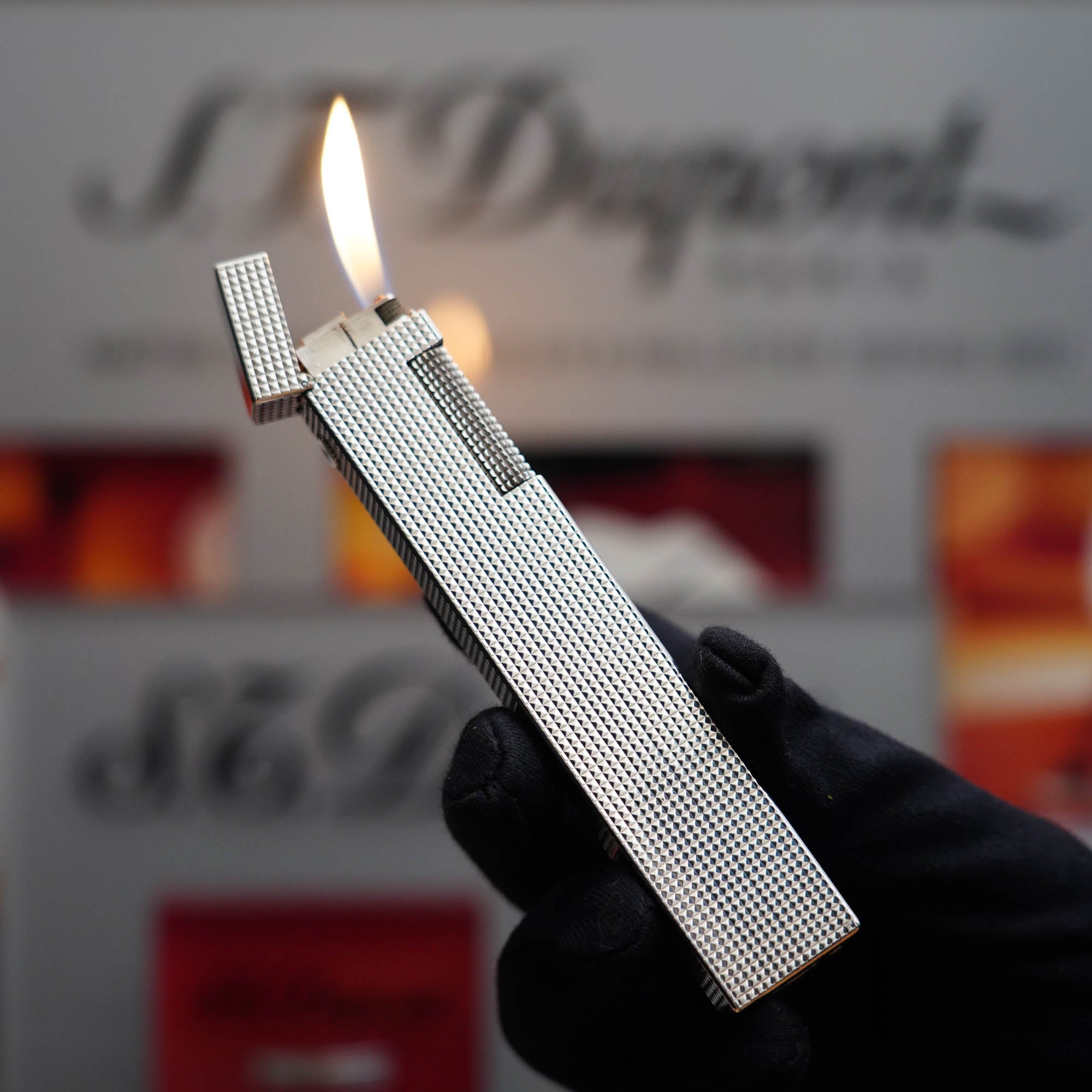 A person is holding a Dunhill Vintage 1970 Dunhill Table lighter Diamond Head Silver Plated Long Boy Lighter in front of a sign.