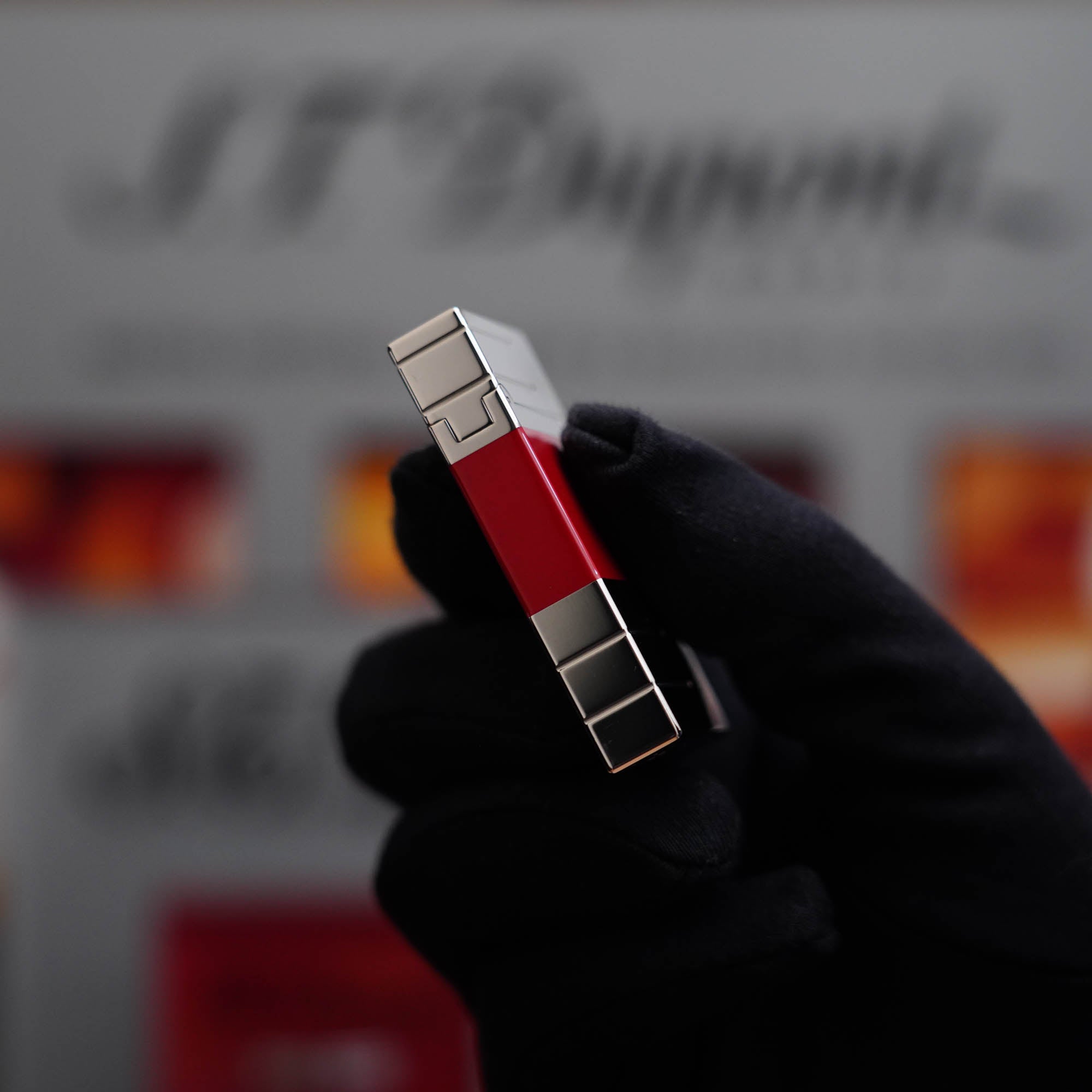 A person is holding up a vintage 1990 Limited Heavy Palladium Finish St Dupont Ligne 2 Abstraction Red Laquer Lighter.