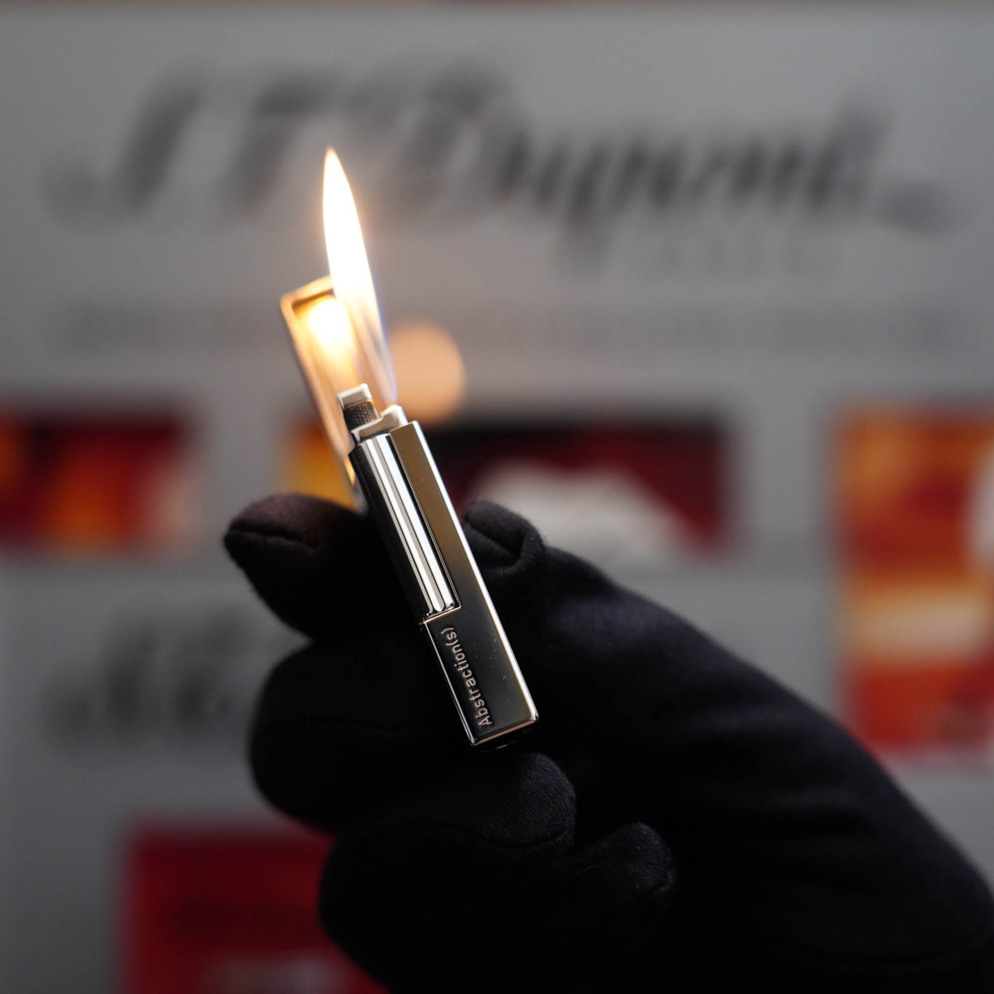 A vintage collector's item featuring a person holding a S.T. Dupont Ligne 2 Abstraction Black Laquer lighter in front of a box.