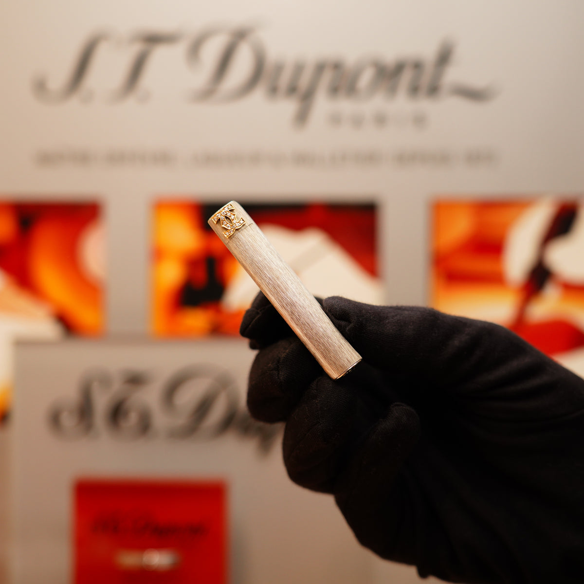 A gloved hand holds a Vintage 1970 Extremely Rare Cartier Solid 925 Sterling Double C lighter with a gold cap, blurred Cartier signage in the background.
