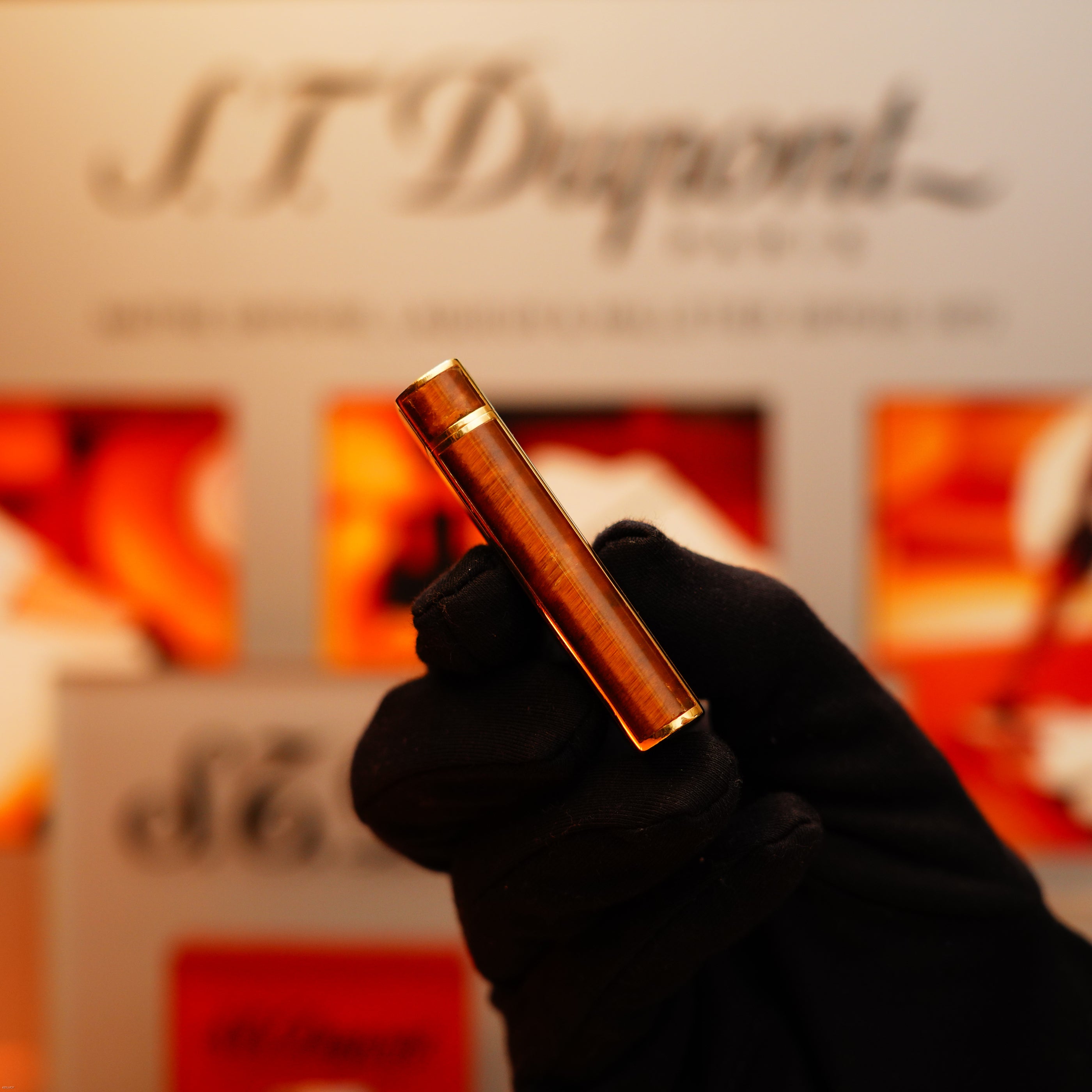 A gloved hand holds a Vintage 1970 Cartier Tiger’s Eye solid 18k lighter with a 750 hallmark, offered by KirbyAllison.com.