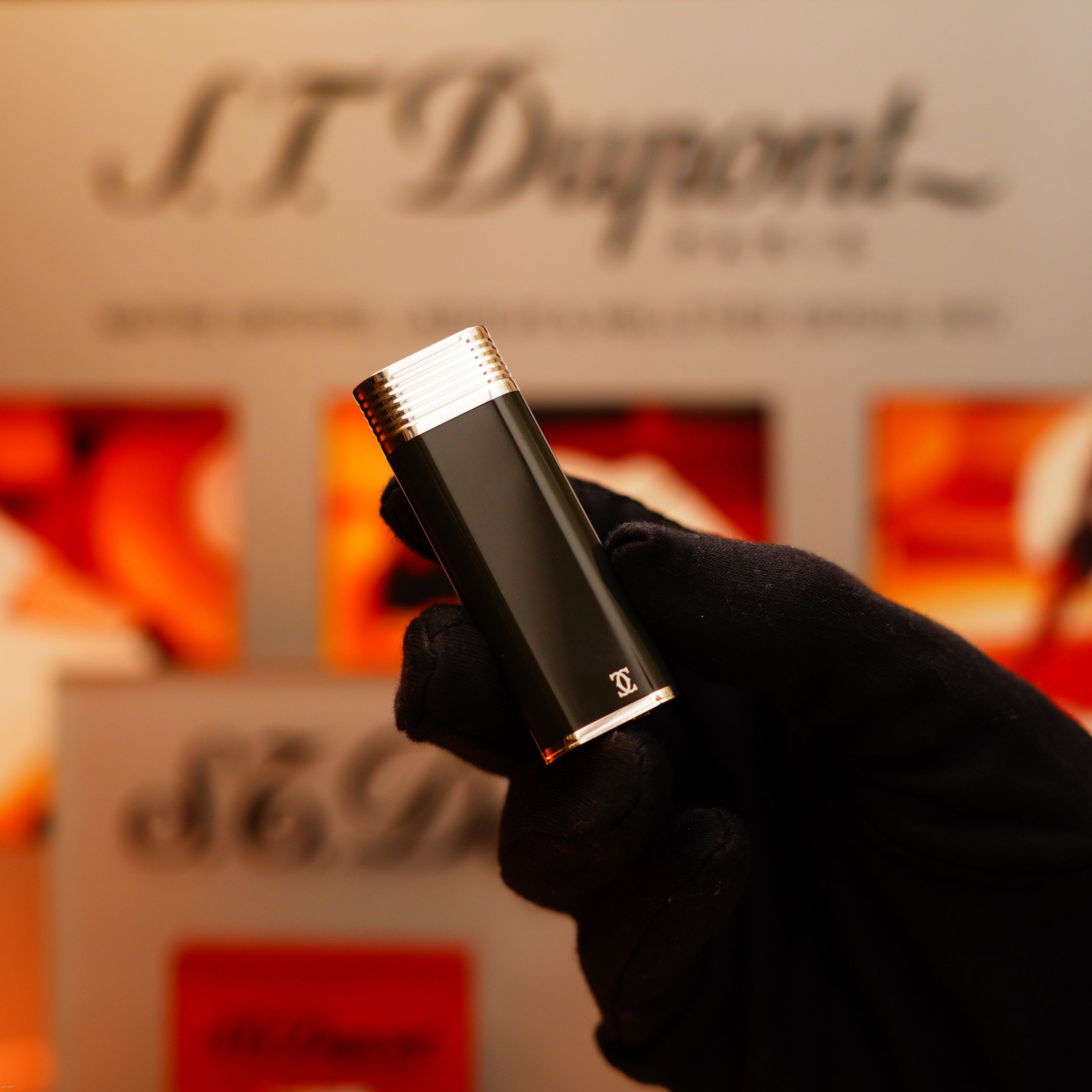 A gloved hand holds a Vintage 1970 Extremely Rare Cartier solid 925 sterling silver lighter with full dark green lacquer by KirbyAllison.com against a blurred display backdrop.