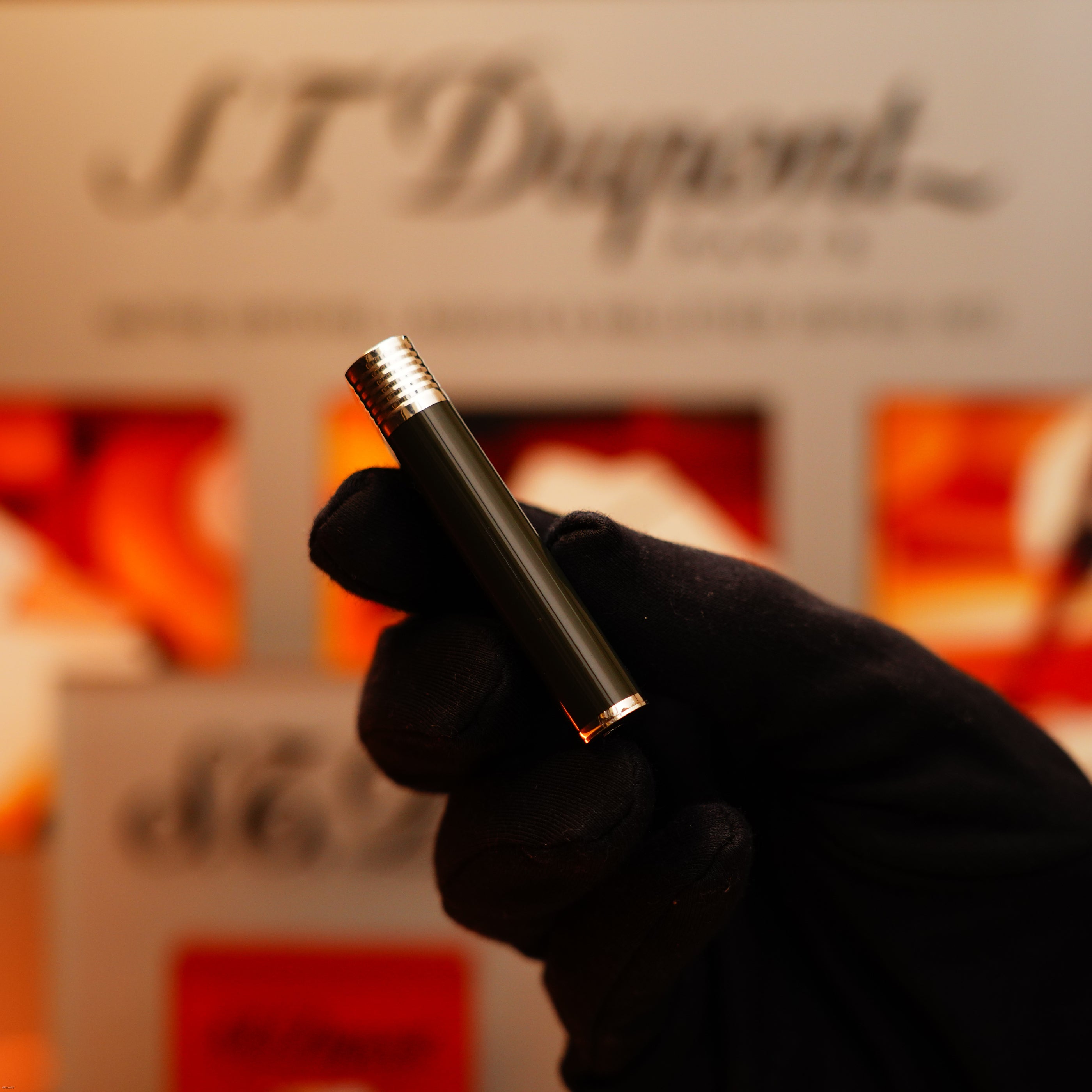 A gloved hand holds a Vintage 1970 Extremely Rare Cartier Solid 925 Sterling Silver Dark Green Lacquer Lighter from KirbyAllison.com in front of a blurred branded background.