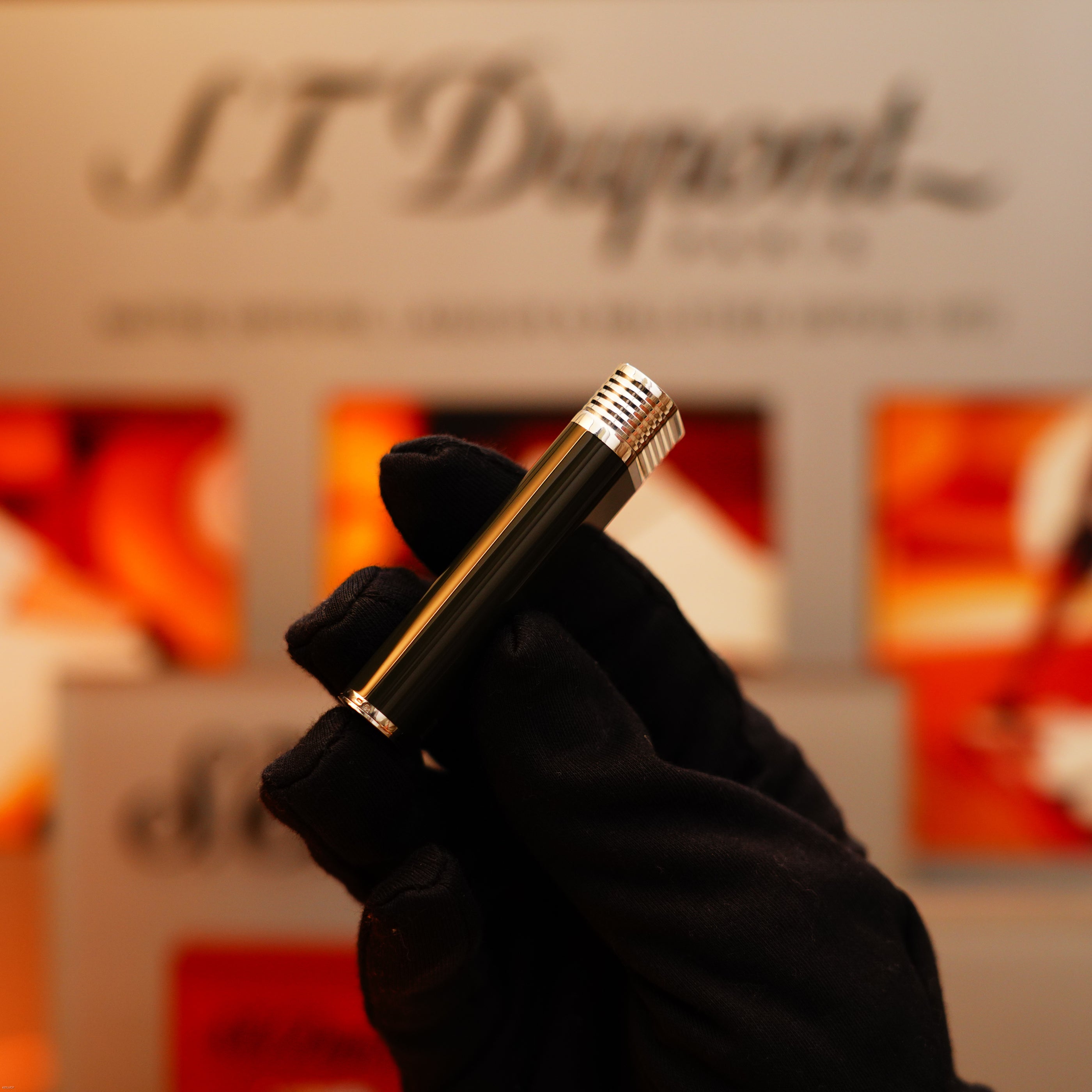 A gloved hand holds a Vintage 1970 Extremely Rare Cartier Solid 925 Sterling Silver Natural Full Dark Green Lacquer Lighter from KirbyAllison.com in front of a blurred display background.