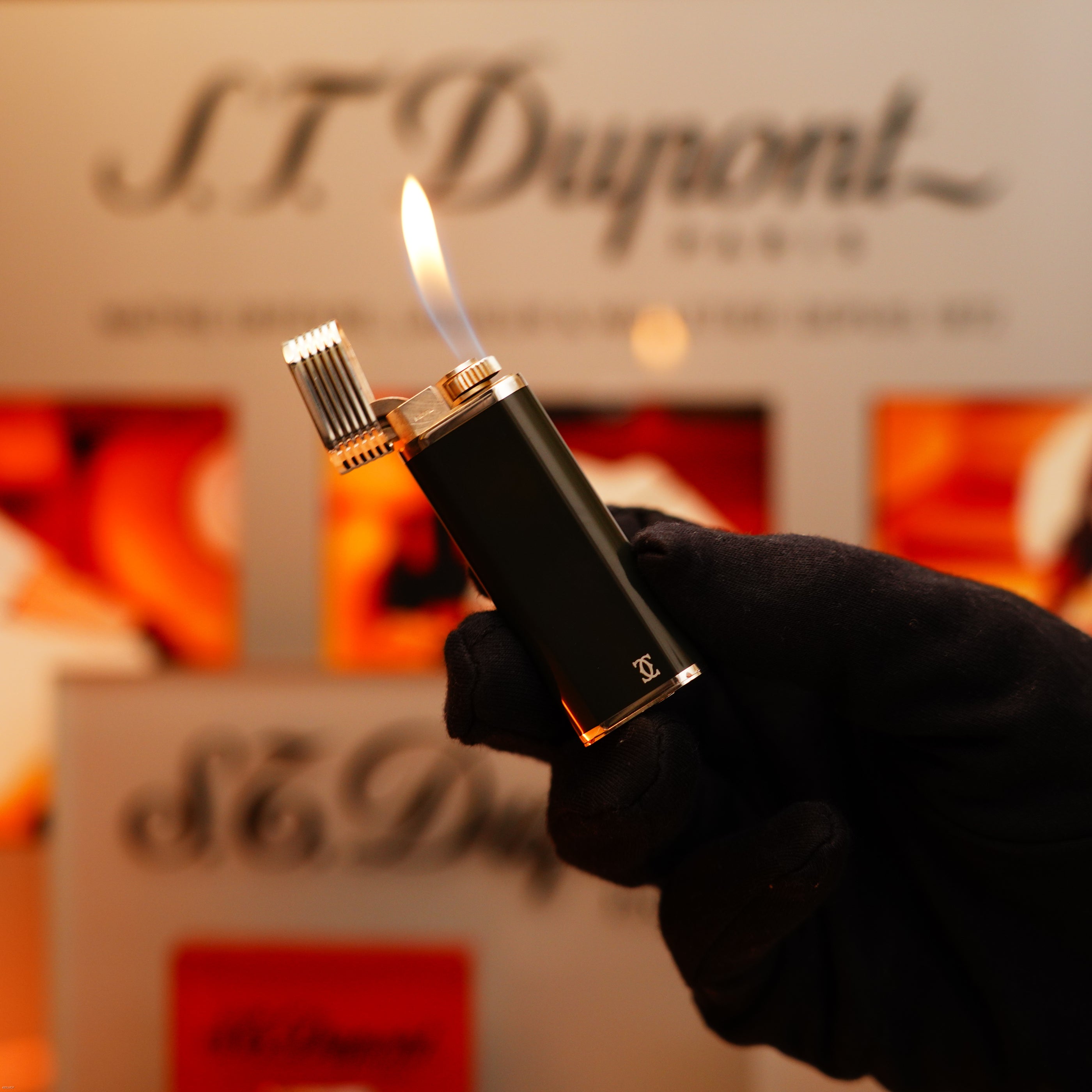 A gloved hand holds a lit Vintage 1970 Extremely Rare Cartier Solid 925 Sterling Silver Dark Green Lacquer Lighter from KirbyAllison.com in front of a blurred display background.