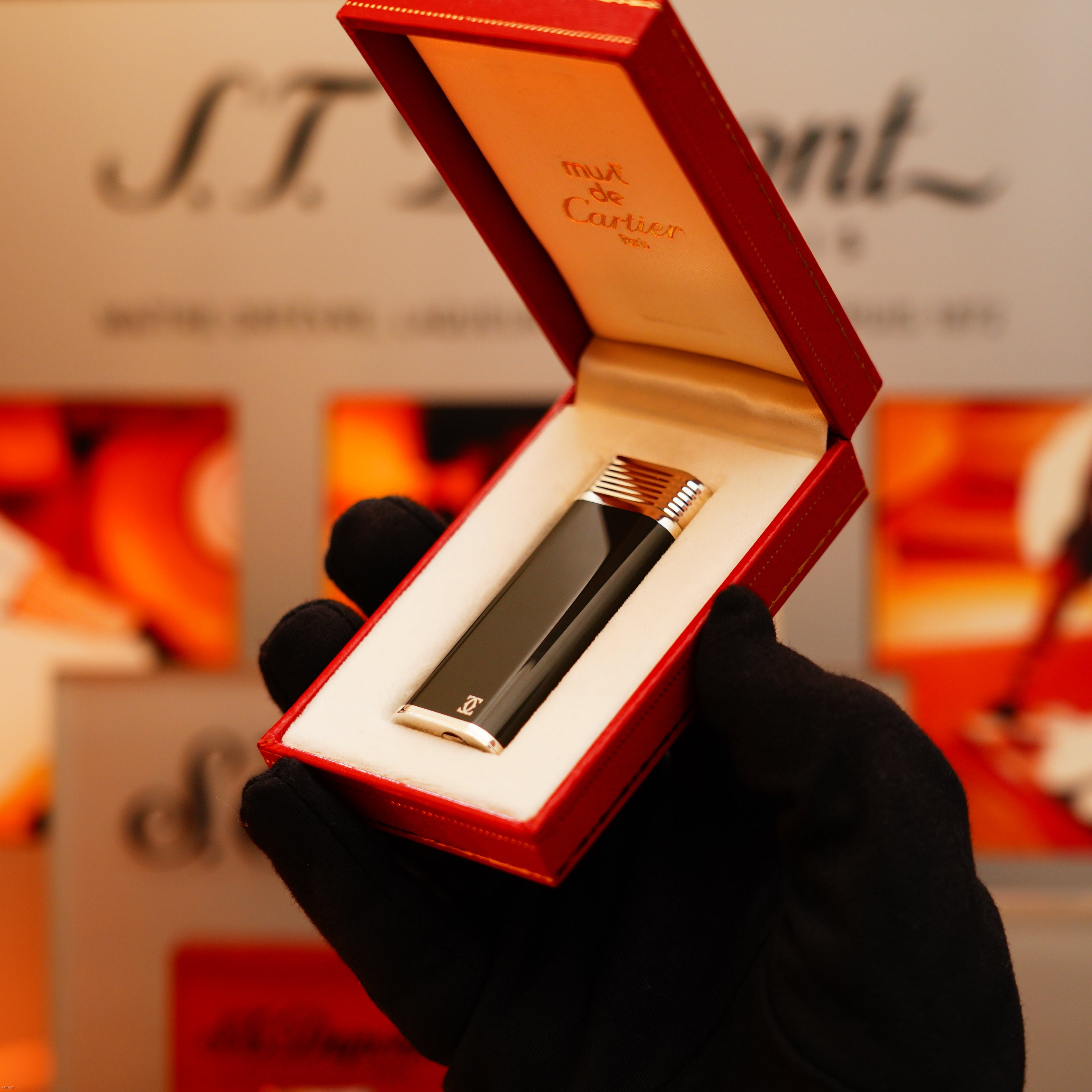 A gloved hand holds an open red box displaying a Vintage 1970 Extremely Rare Cartier Solid 925 Sterling Silver Natural Full Dark Green Lacquer Rare Lighter from KirbyAllison.com, set against a blurred background.