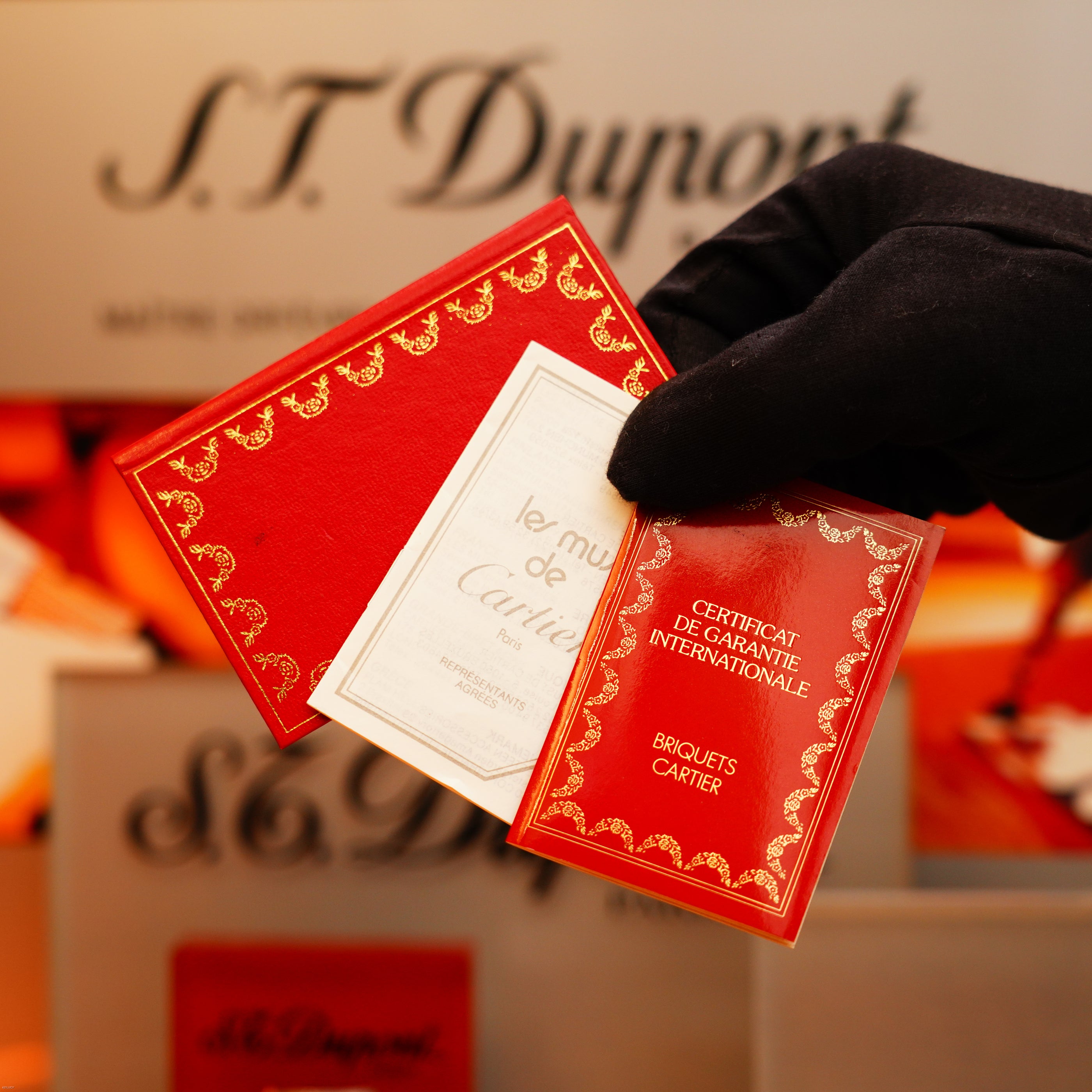 A gloved hand holds two red and gold certificates labeled "Cartier" and "Certificat de Garantie Internationale" in front of a KirbyAllison.com Vintage 1970 Rare Cartier Solid 925 Sterling Silver Green Lacquer Lighter display.