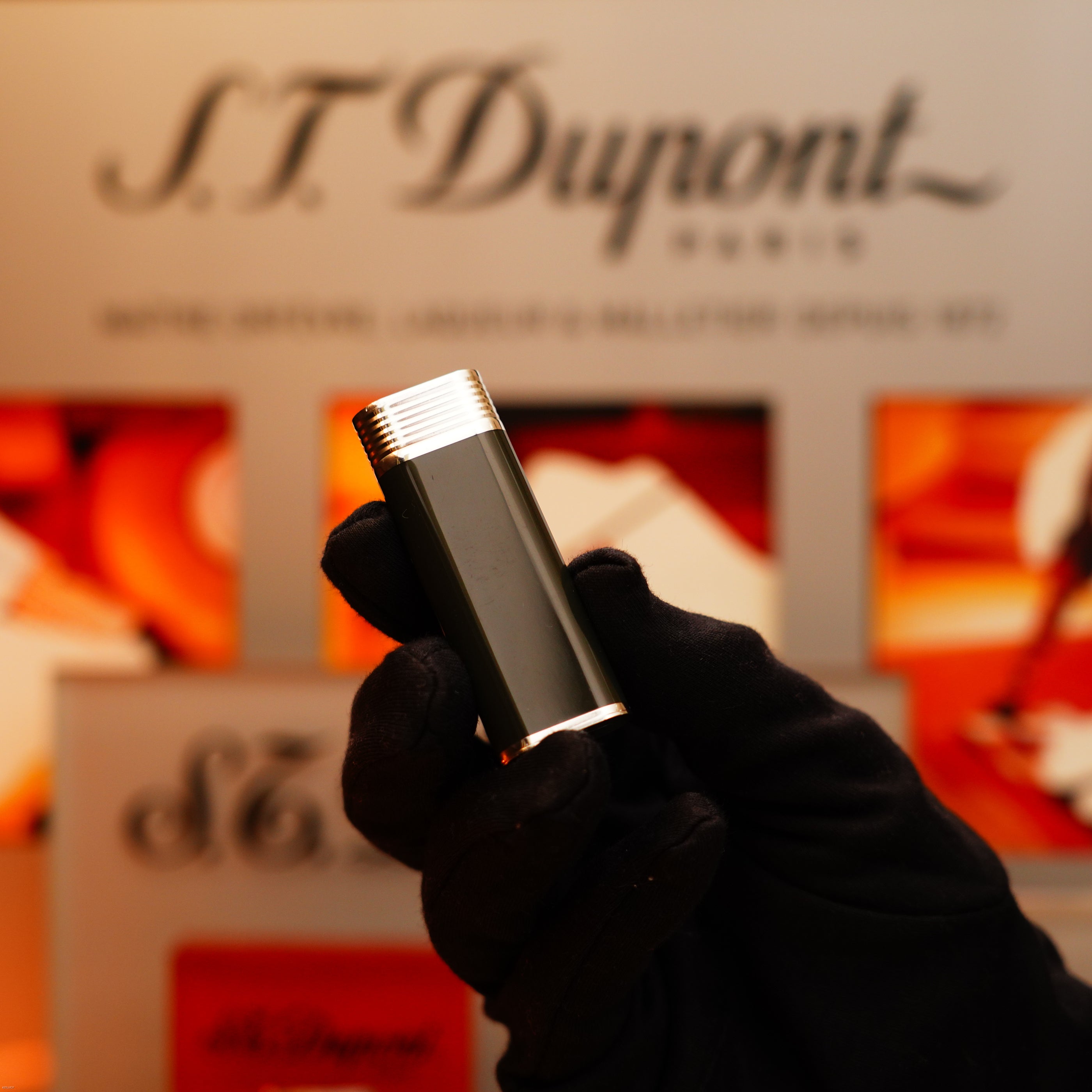 A gloved hand holds a Vintage 1970 Extremely Rare Cartier Solid 925 Sterling Silver Natural Full Dark Green Lacquer Rare Lighter from KirbyAllison.com in front of an S.T. Dupont Paris display.