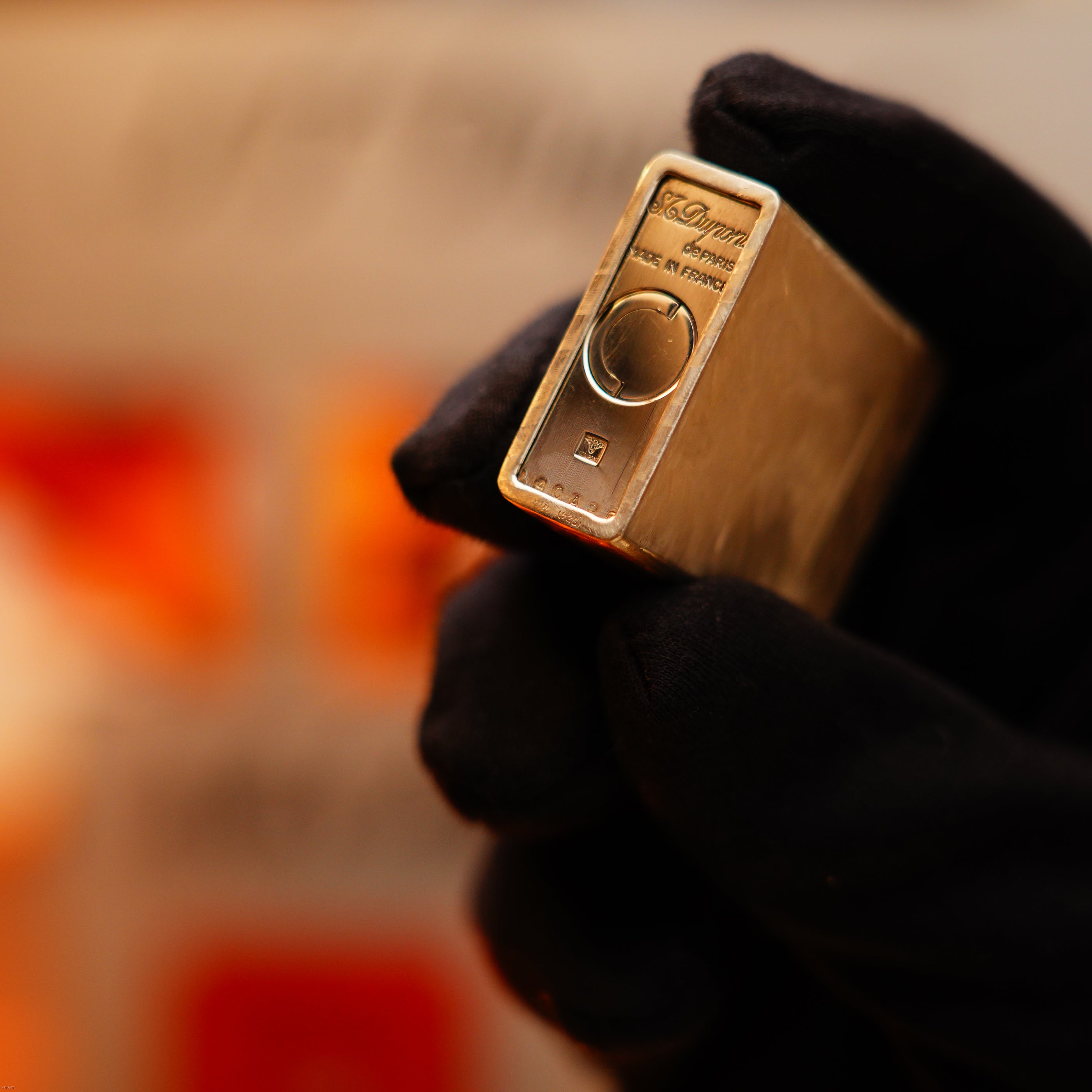 A gloved hand holds a small rectangular gold-colored device labeled "S.T. Dupont," identified as a Vintage 1970 de St Dupont Two Tone Solid 925 Sterling Silver Guilloché Pattern Lighter with a rotary dial and button.