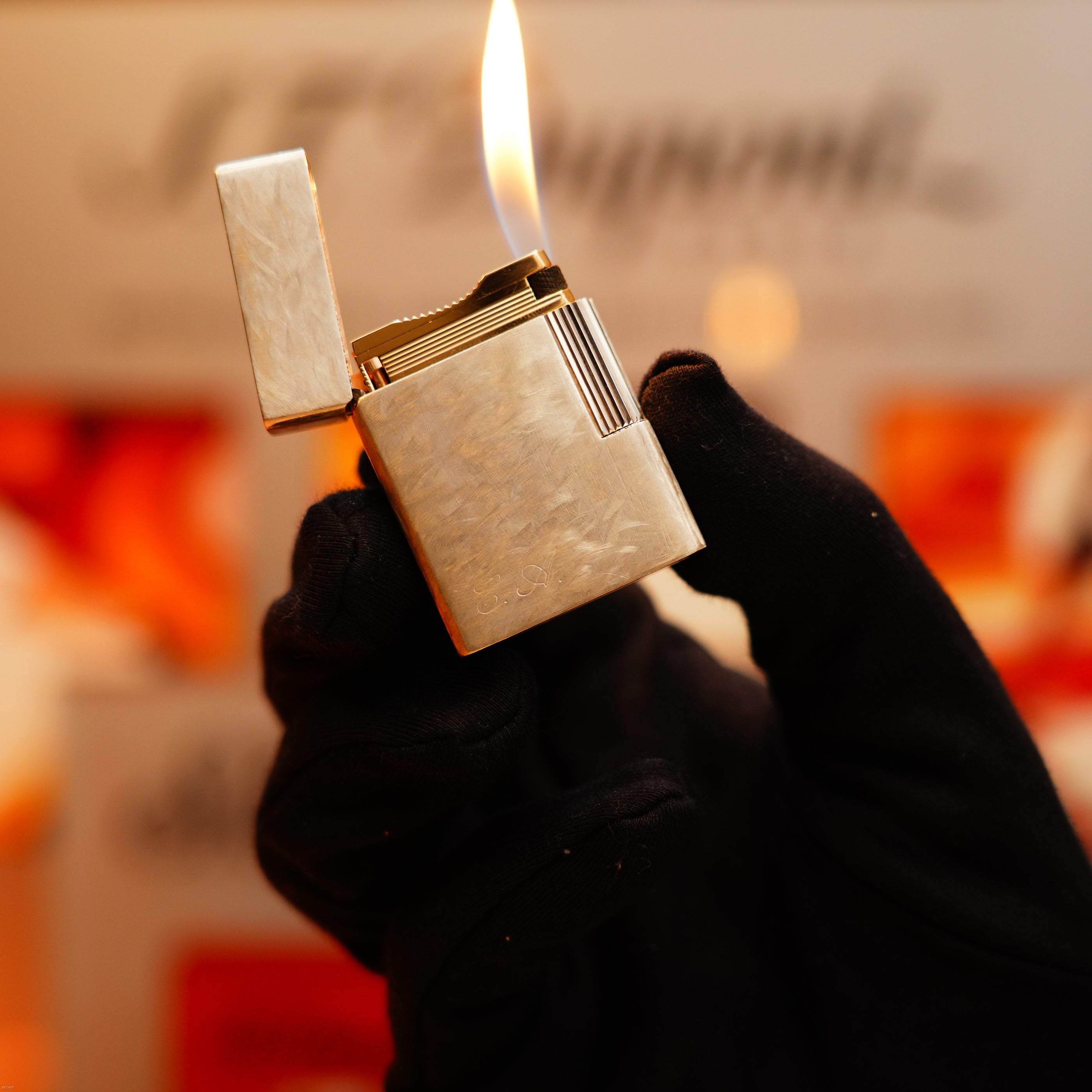 A gloved hand holds an open Vintage 1970 S.T. Dupont Two Tone Solid 925 Sterling Silver Guilloché Pattern Lighter with a flame burning.