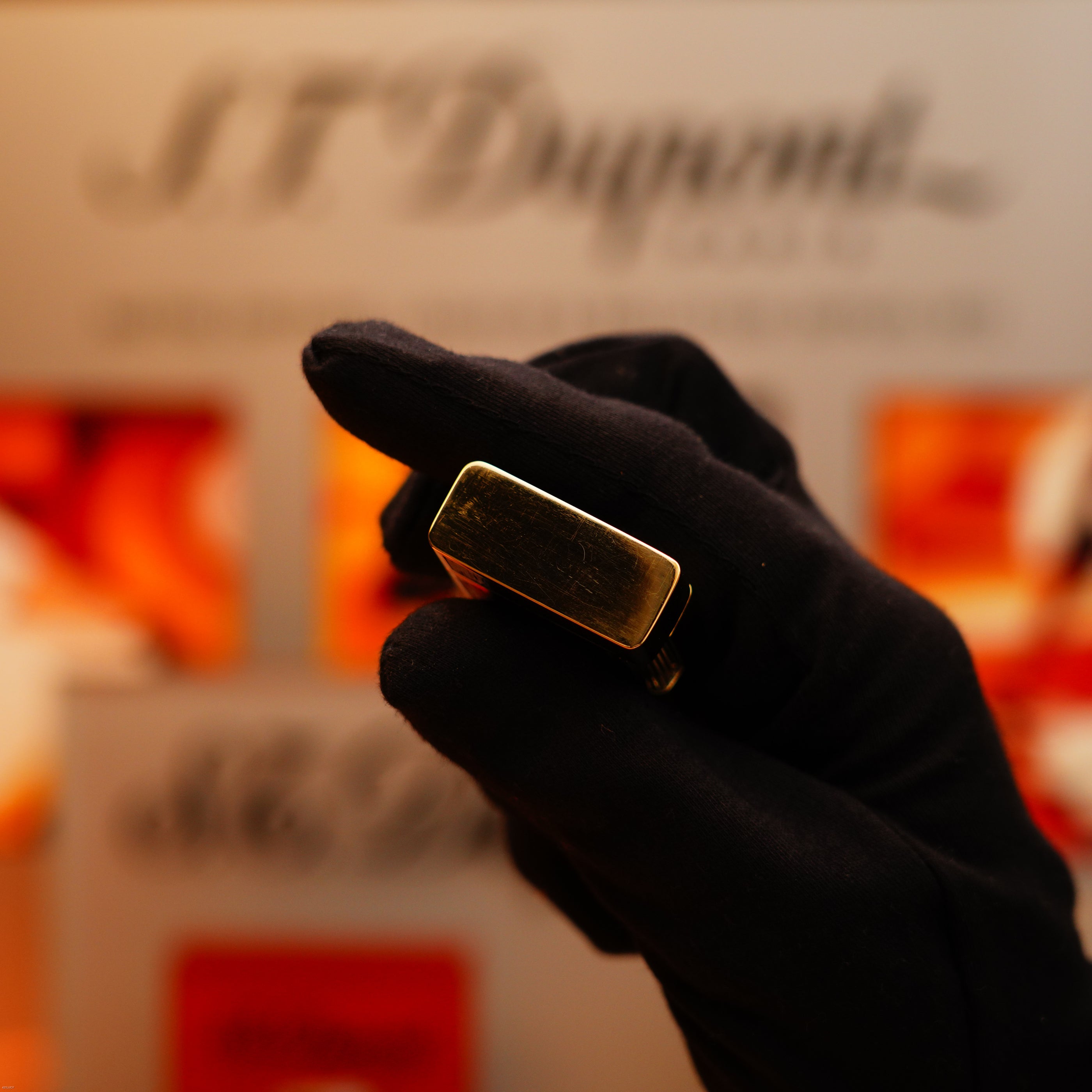 A gloved hand holds a Vintage 1970 Rare S.T. Dupont Solid 18k Gold and Natural Wood Lighter, with "S.T. Dupont" visible against a blurred background.