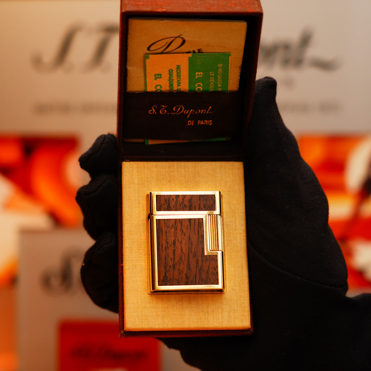 A gloved hand holds an open S.T. Dupont box with a Vintage 1970 Rare St Dupont Solid 18k Gold and Natural Wood Work 750 hallmarked Lighter, plus instruction booklets inside the lid.