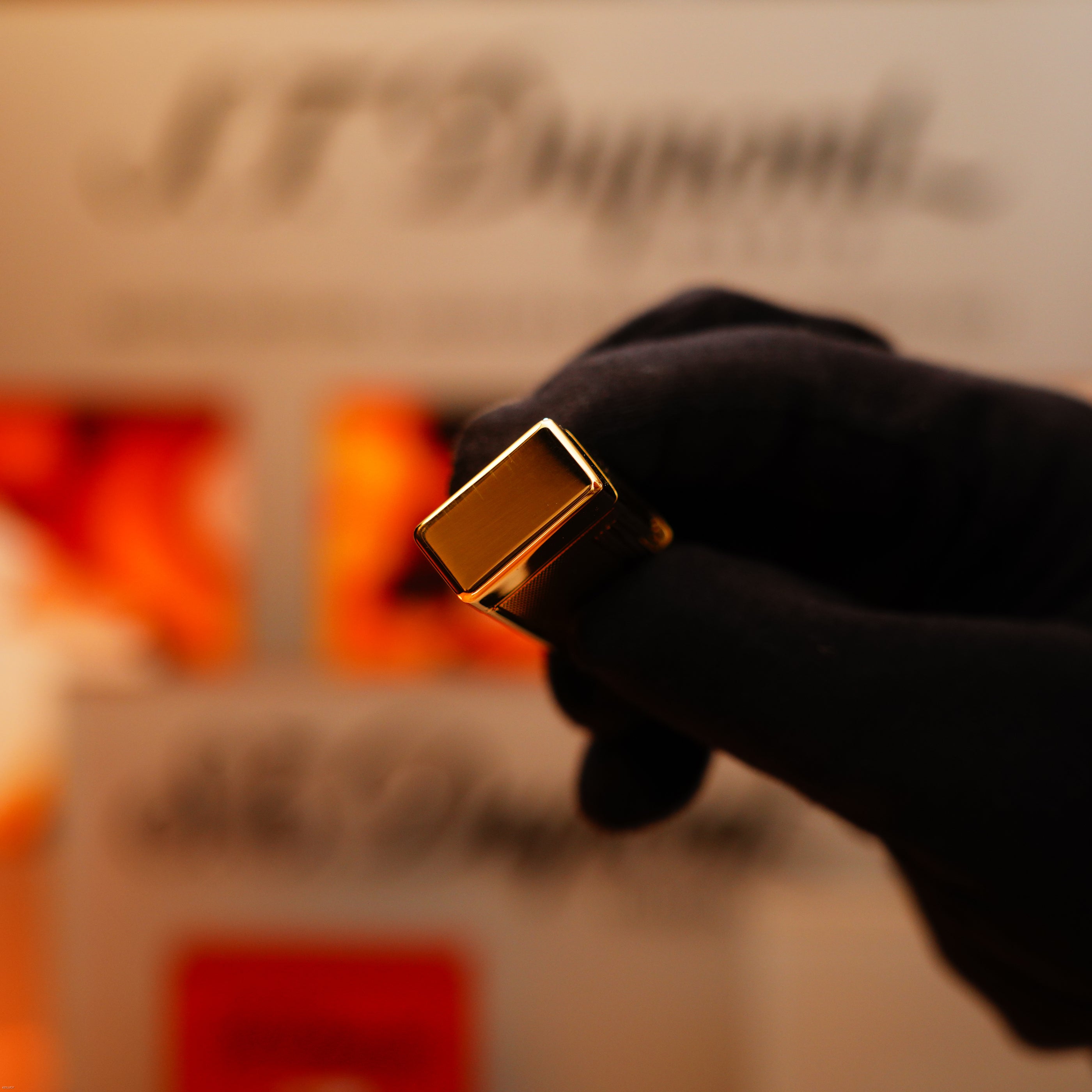A gloved hand holds a Vintage 1964 Oct. Dunhill Rollagas solid 18k gold lighter with a 750 hallmark; an extremely heavy early production piece by Dunhill is in focus, while the background is blurred.