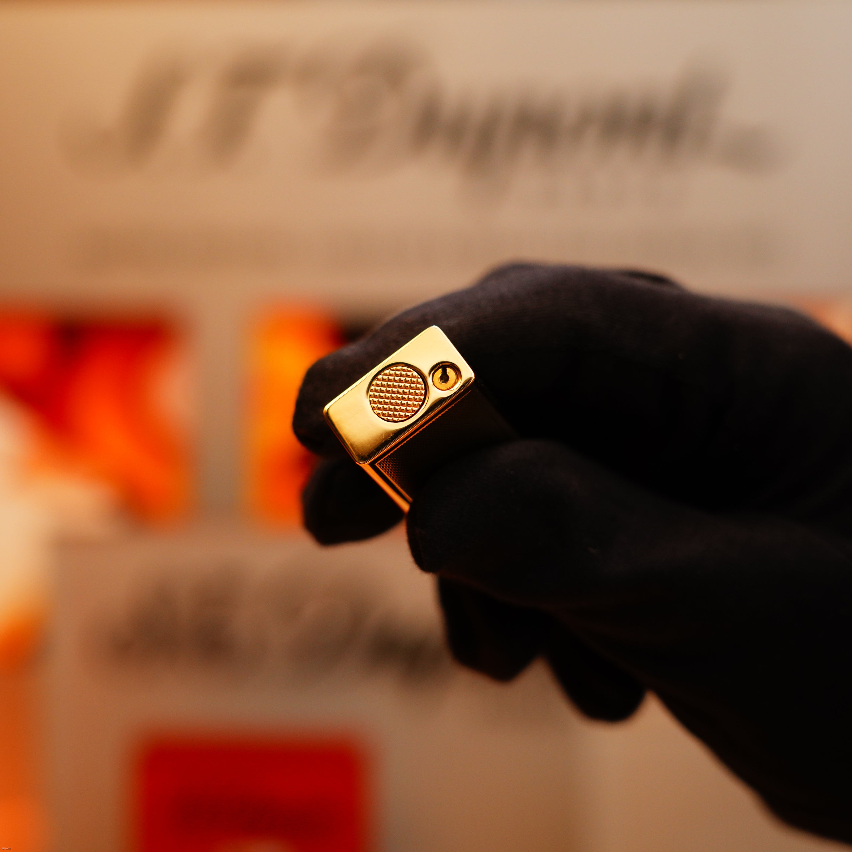 A hand wearing a black glove holds a Vintage 1964 Oct. Dunhill Rollagas solid 18k gold lighter (750 hallmark, extremely heavy) against a blurred background.