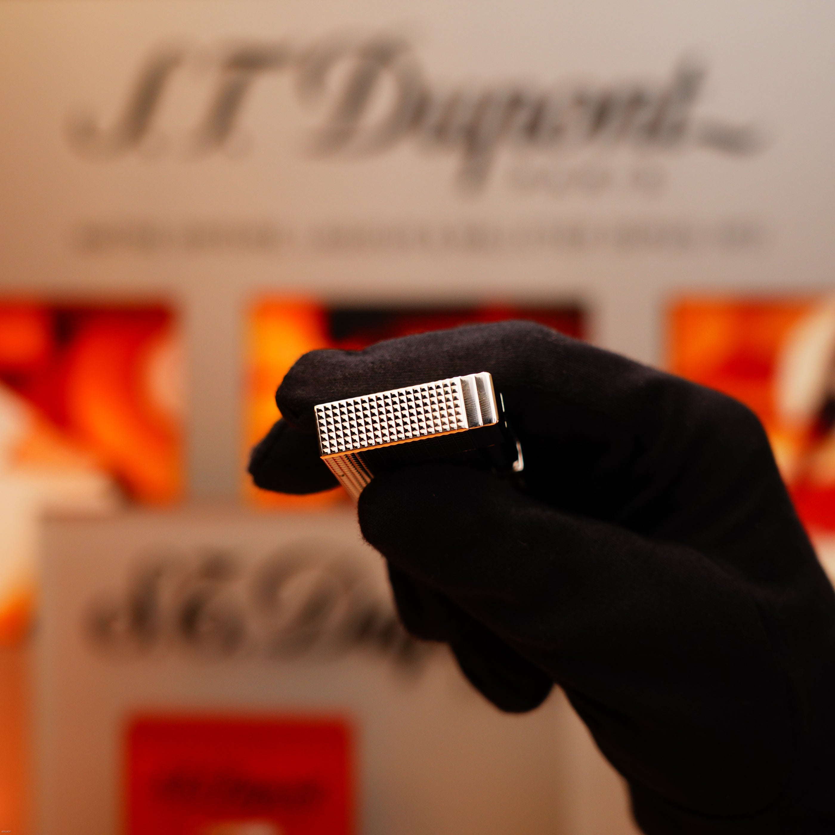 A gloved hand holds the Vintage 2005 S.T. Dupont Gatsby Diamond Drops Limited Edition Lighter with 16 natural diamonds and heavy platinum; blurred S.T. Dupont branding appears in the background.