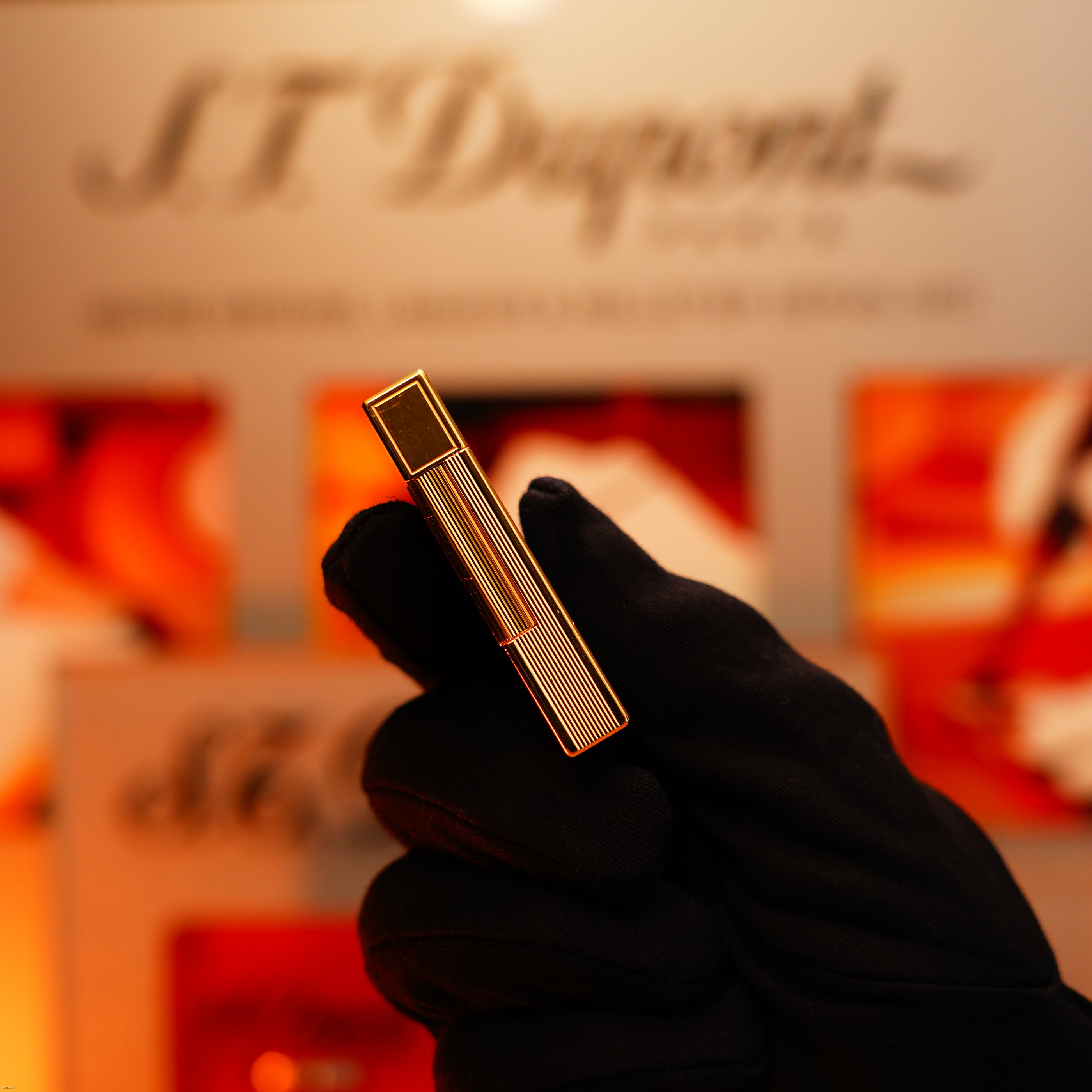 A gloved hand holds a Vintage 1993 Lucy Lighter Europe Rare 24k Gold Finish Blue Lacquer Limited Edition Ligne 2, with a blurred branded background.