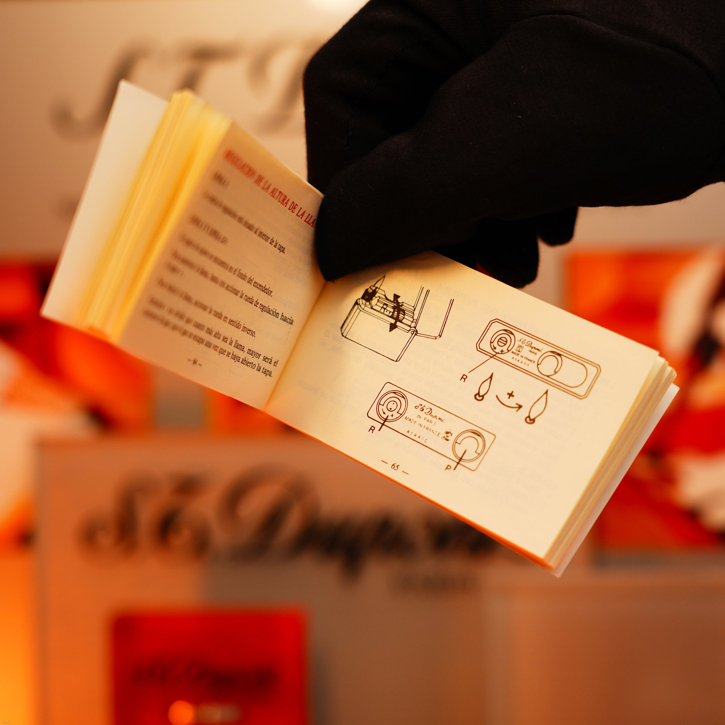 A gloved hand flips through a manual with diagrams, set against a blurred background with the Lucy Lighter logo, offering guidance on warranty and care for your Vintage 1993 St Dupont Europe Rare 24k Gold Finish Blue Lacquer Limited Edition Ligne 2 Lighter.