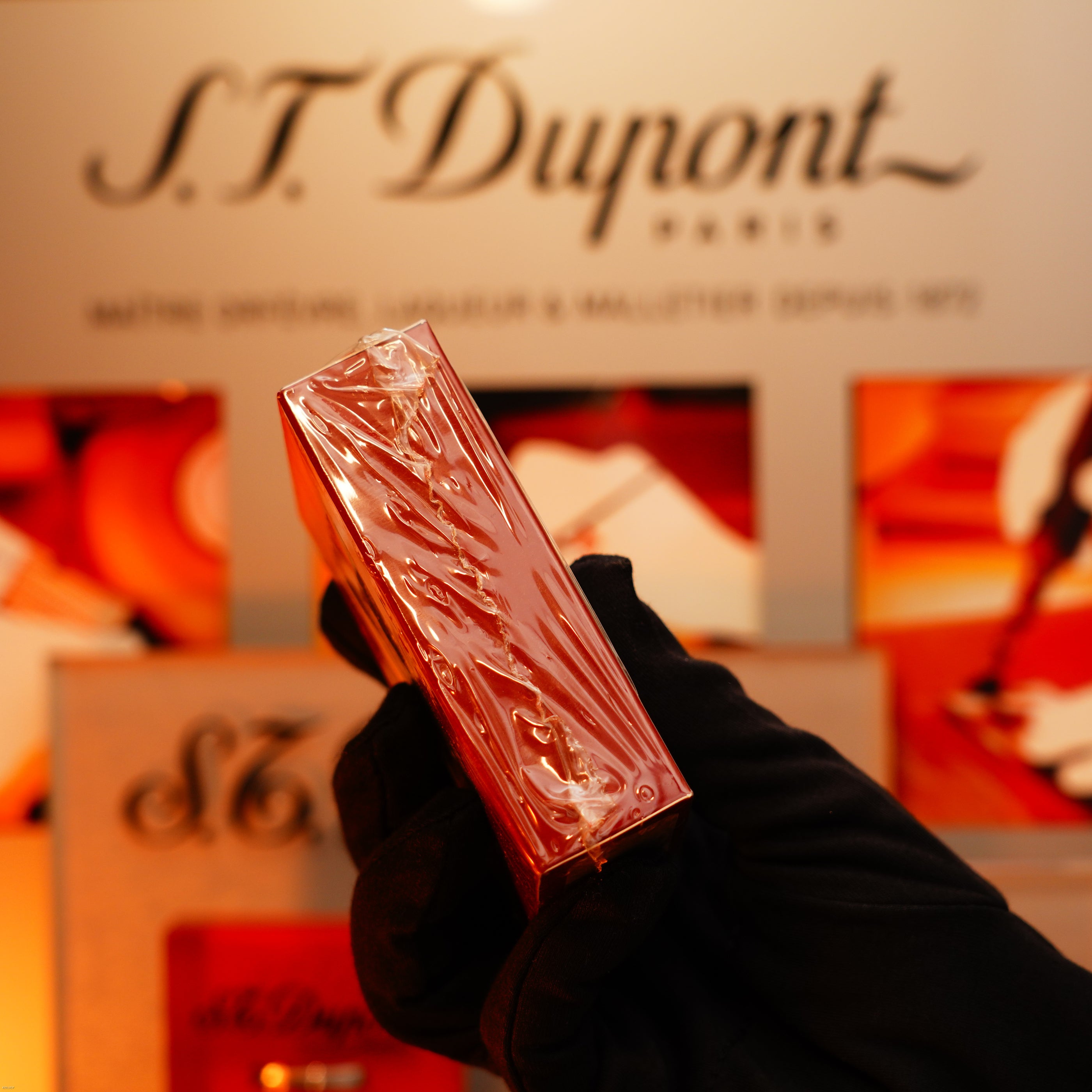 A gloved hand holds a shrink-wrapped Vintage 1990 Lucy Lighter—Heavy Silver iconic Vertical ligne rare Sealed Lighter—in front of an S.T. Dupont Paris display.