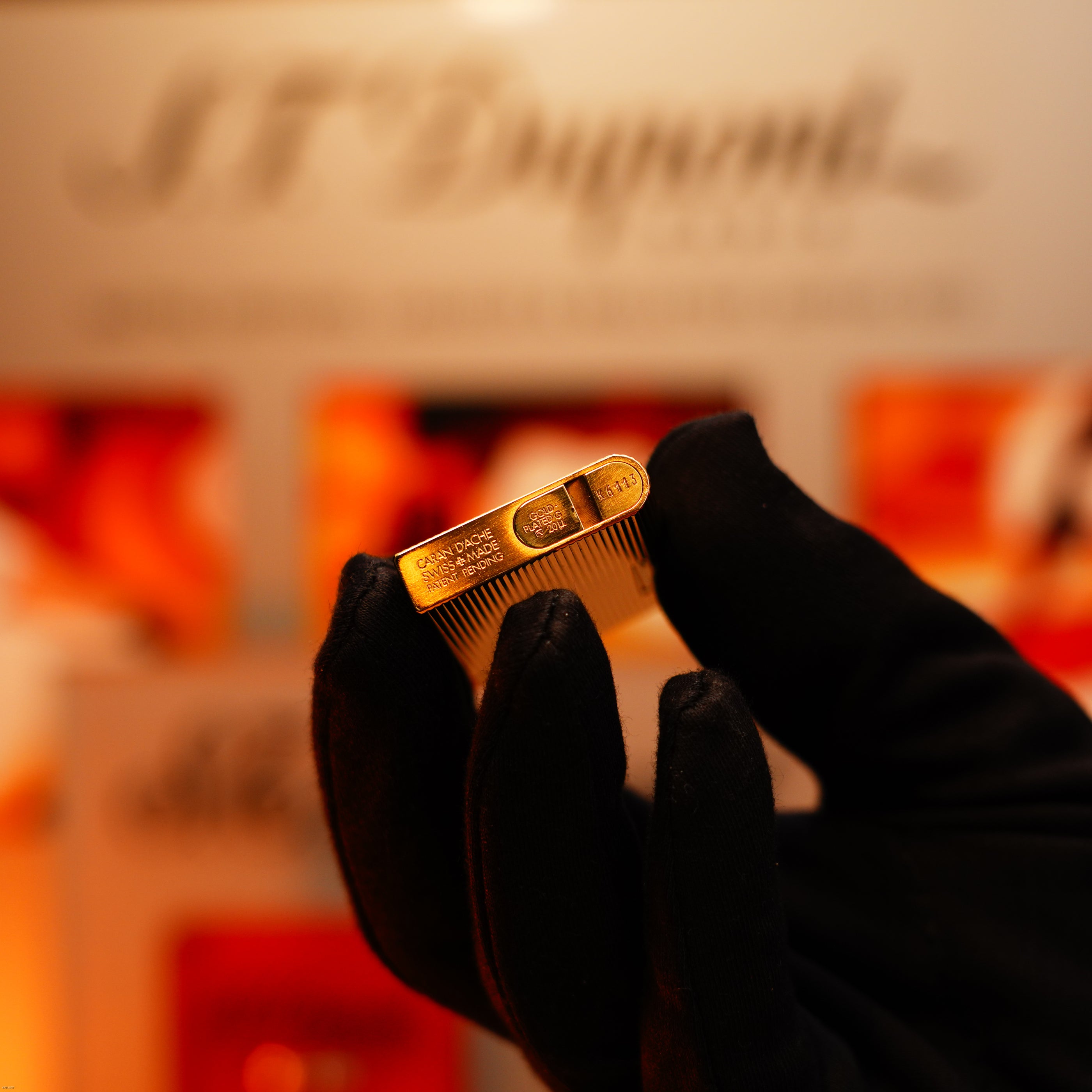 A gloved hand holds the Vintage 1970 Heavy 24k Gold Finish Caran d'Ache Limited Madison Lighter by Lucy Lighter—a rare Swiss luxury piece, possibly covered by a 12-month warranty against functional issues.