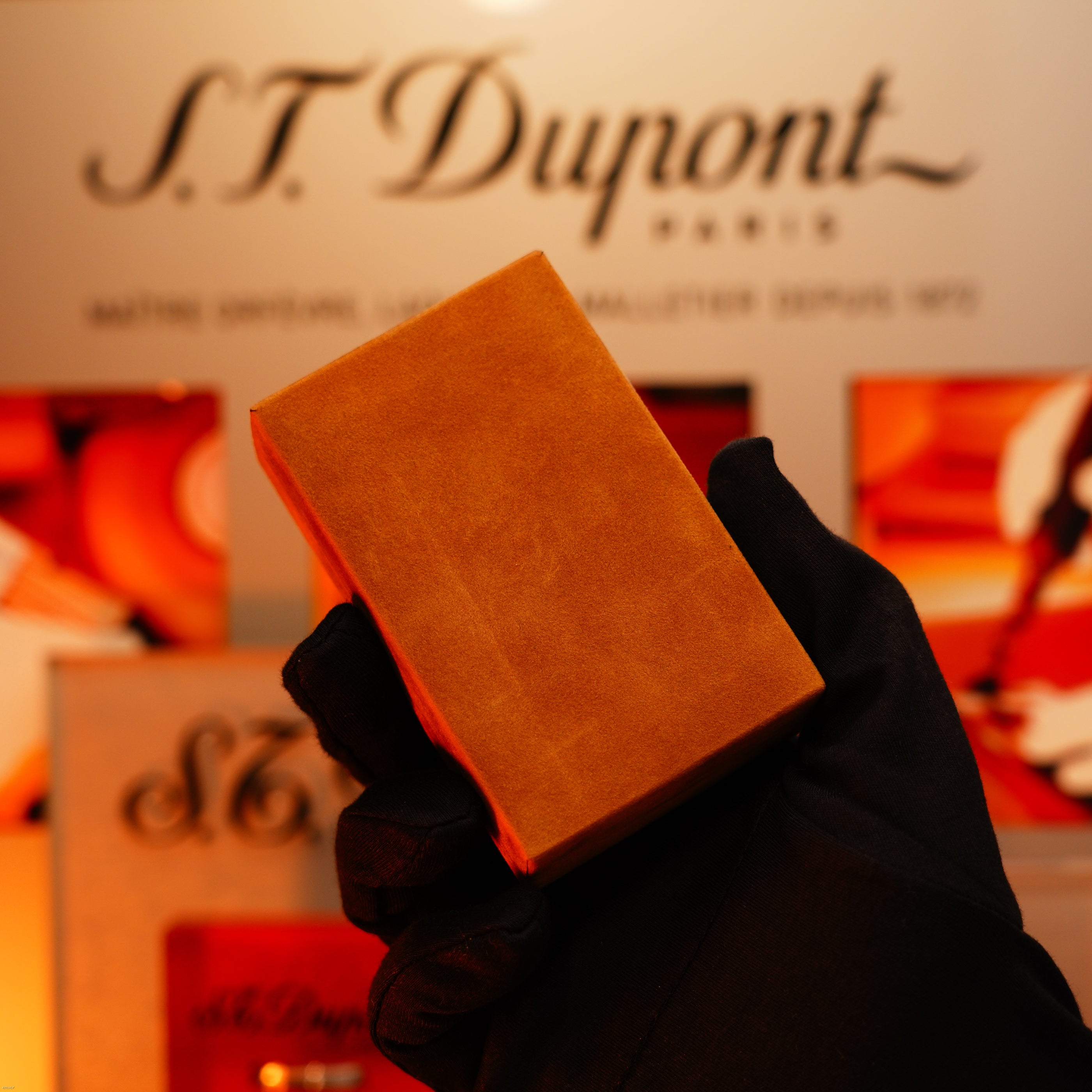 A gloved hand holds a Vintage 1970 Heavy 24k Gold Finish Caran d'ache Limited Madison Swiss Lighter by Lucy Lighter in front of a display background.