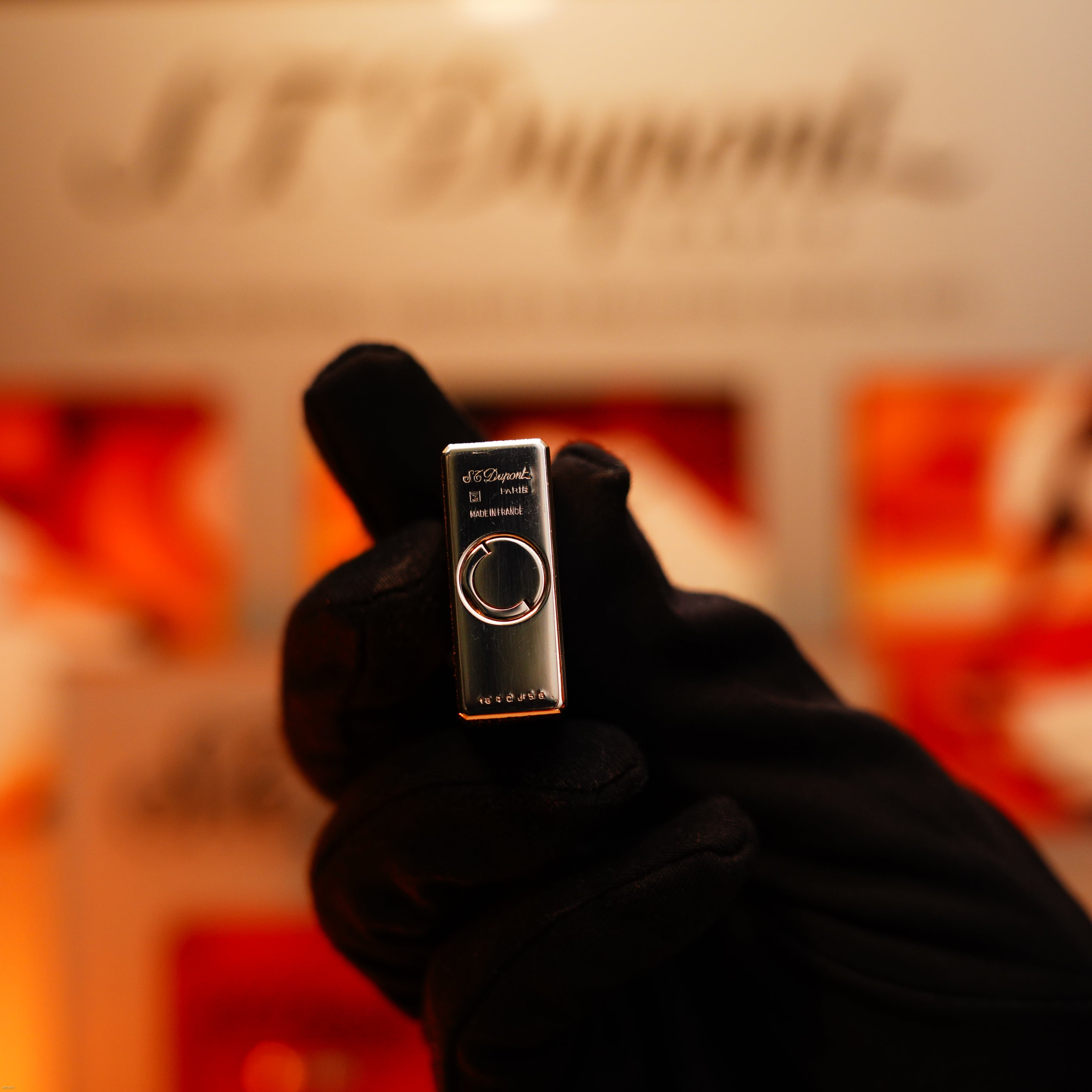 A gloved hand displays a Vintage 1980 St Dupont Heavy Silver Finish Ligne 1 Large Lighter in a rare pattern from Lucy Lighter, with branding and model details visible against a blurred background to showcase its quality.