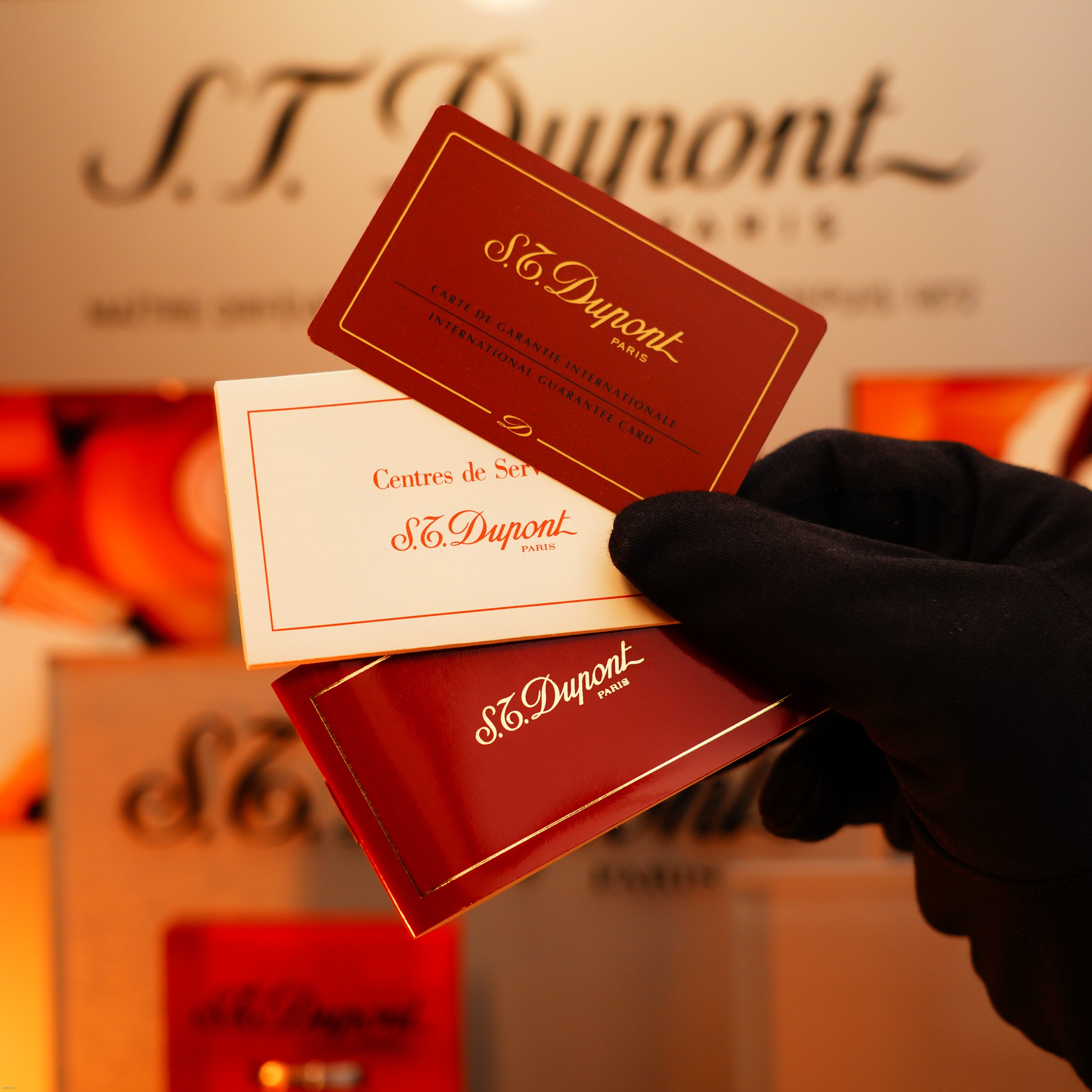 A gloved hand holds three Lucy Lighter cards in red and white, with the logo in the background—highlighting a quality guarantee for your Vintage 1980 St Dupont Heavy Silver Finish Ligne 1 Large size Rare Pattern Lighter.